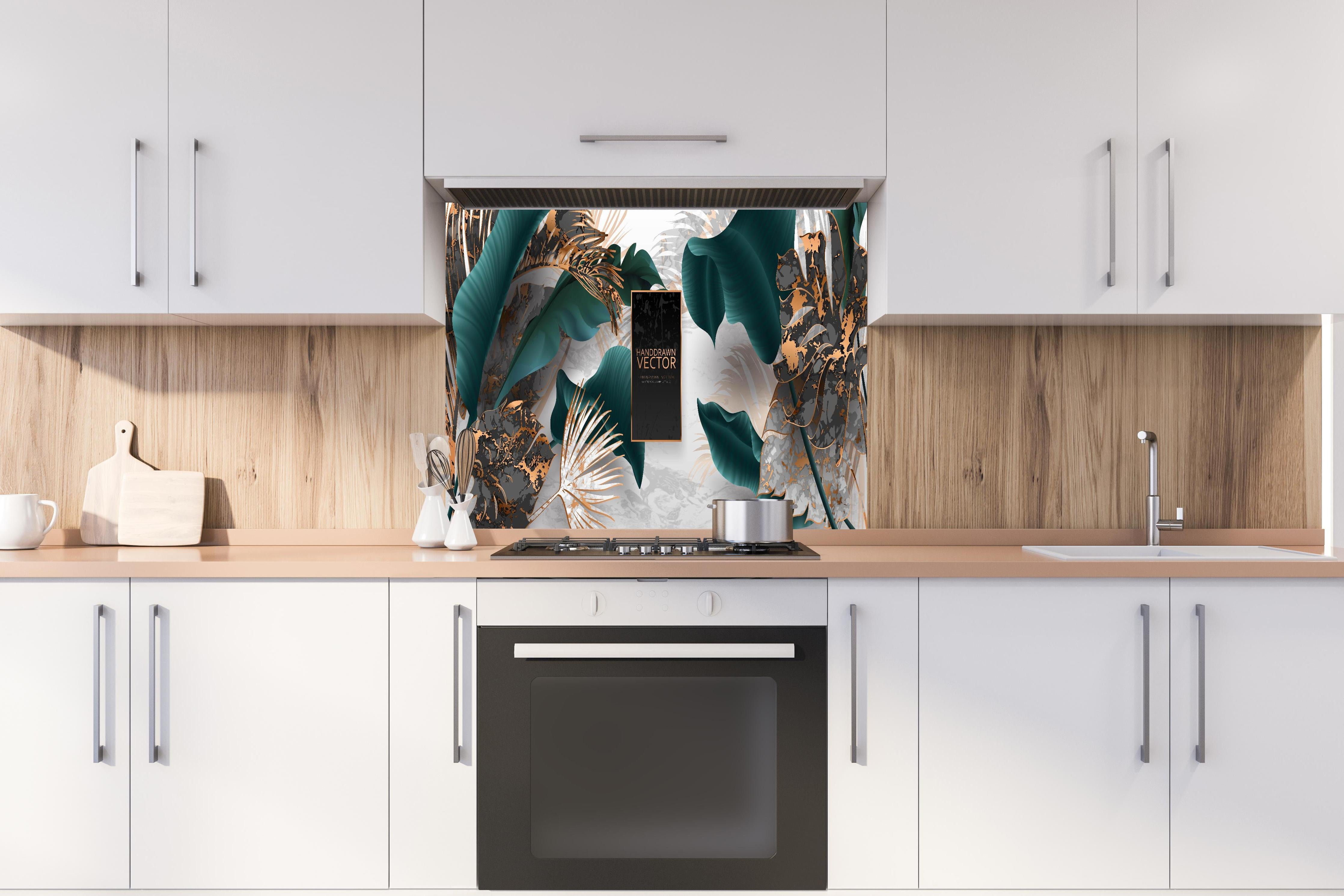 Spritzschutz - Grüne Tropenblätter mit goldenen Akzenten hinter einem Cerankochfeld zwischen Holz-Kochutensilien