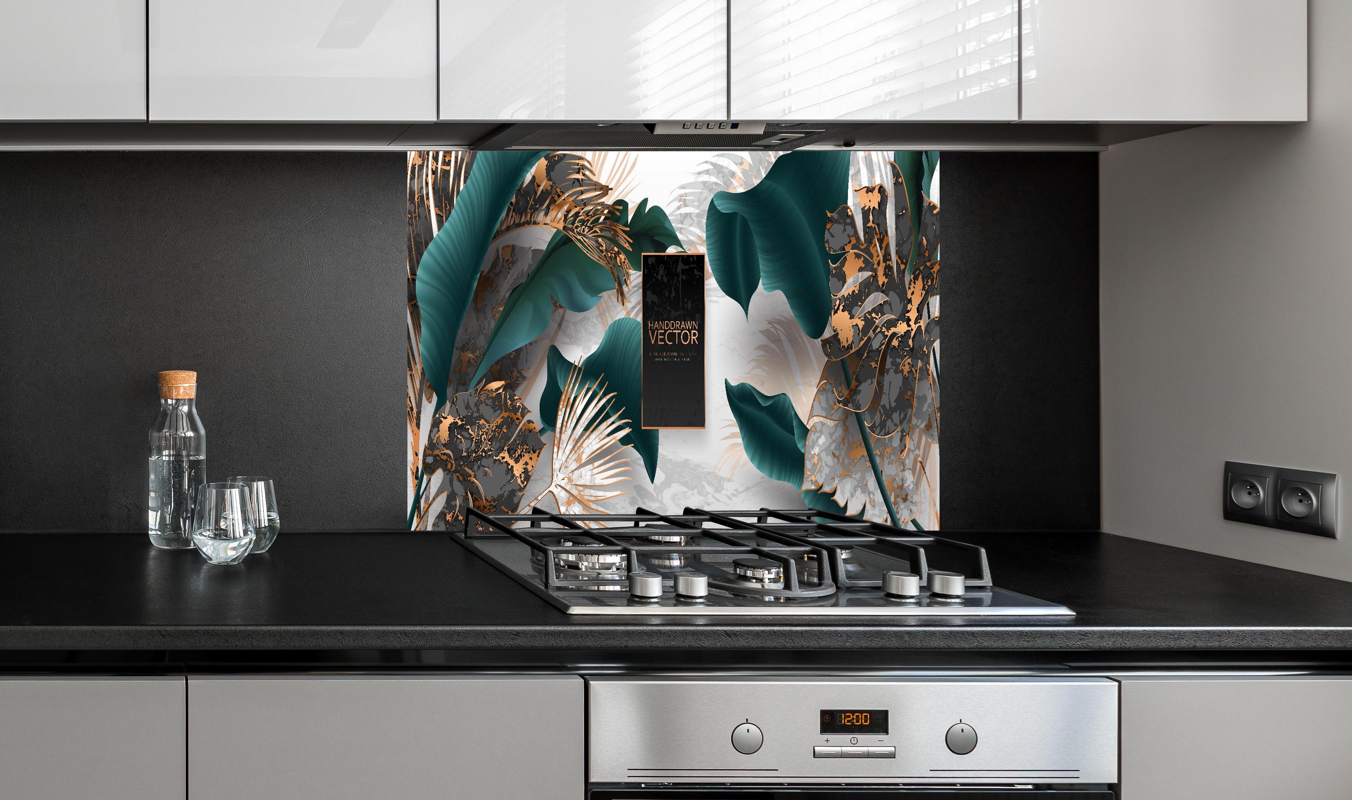 Spritzschutz - Grüne Tropenblätter mit goldenen Akzenten hinter einem Cerankochfeld zwischen Holz-Kochutensilien