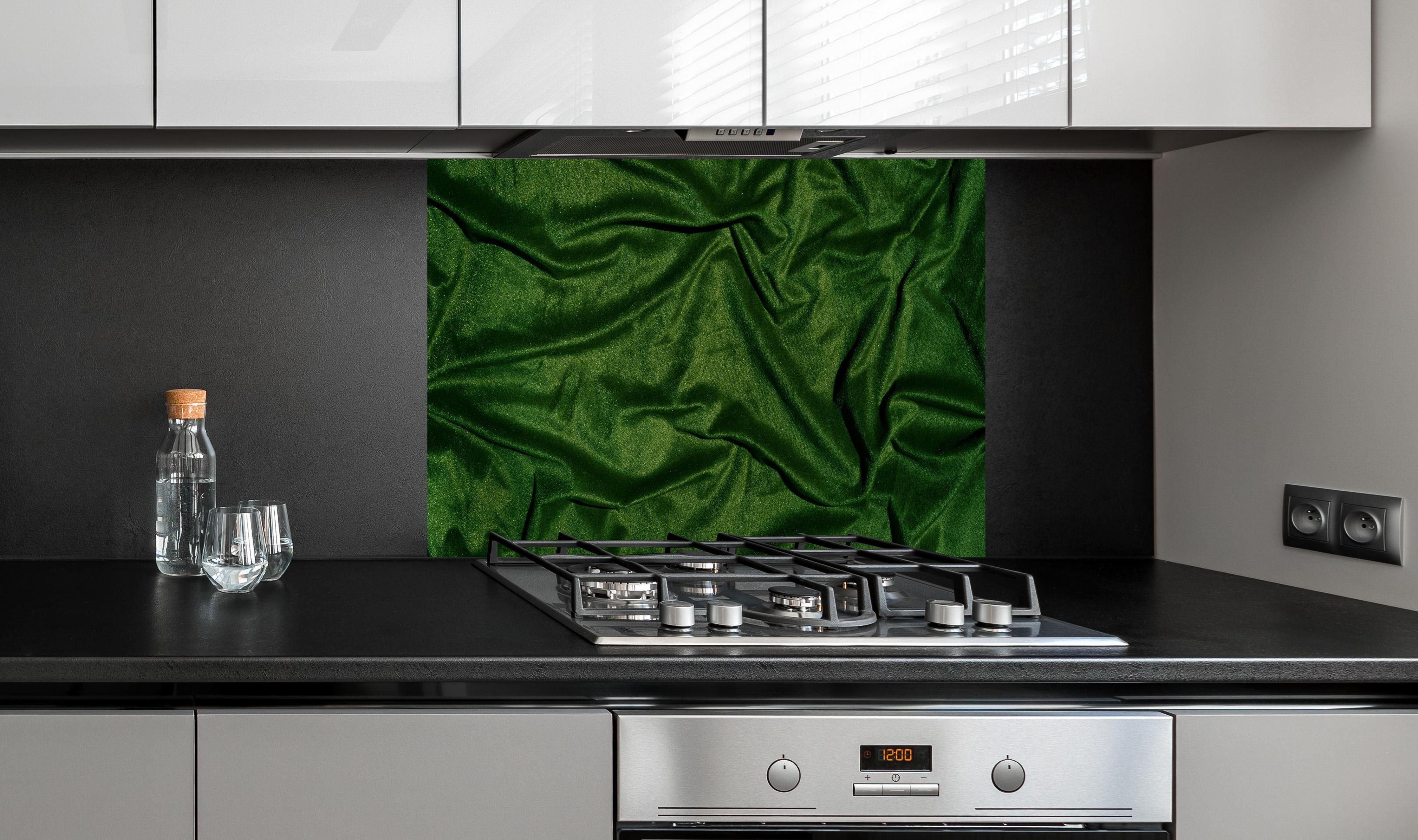 Spritzschutz - Grüner Seidenstoff Hintergrund hinter einem Cerankochfeld zwischen Holz-Kochutensilien