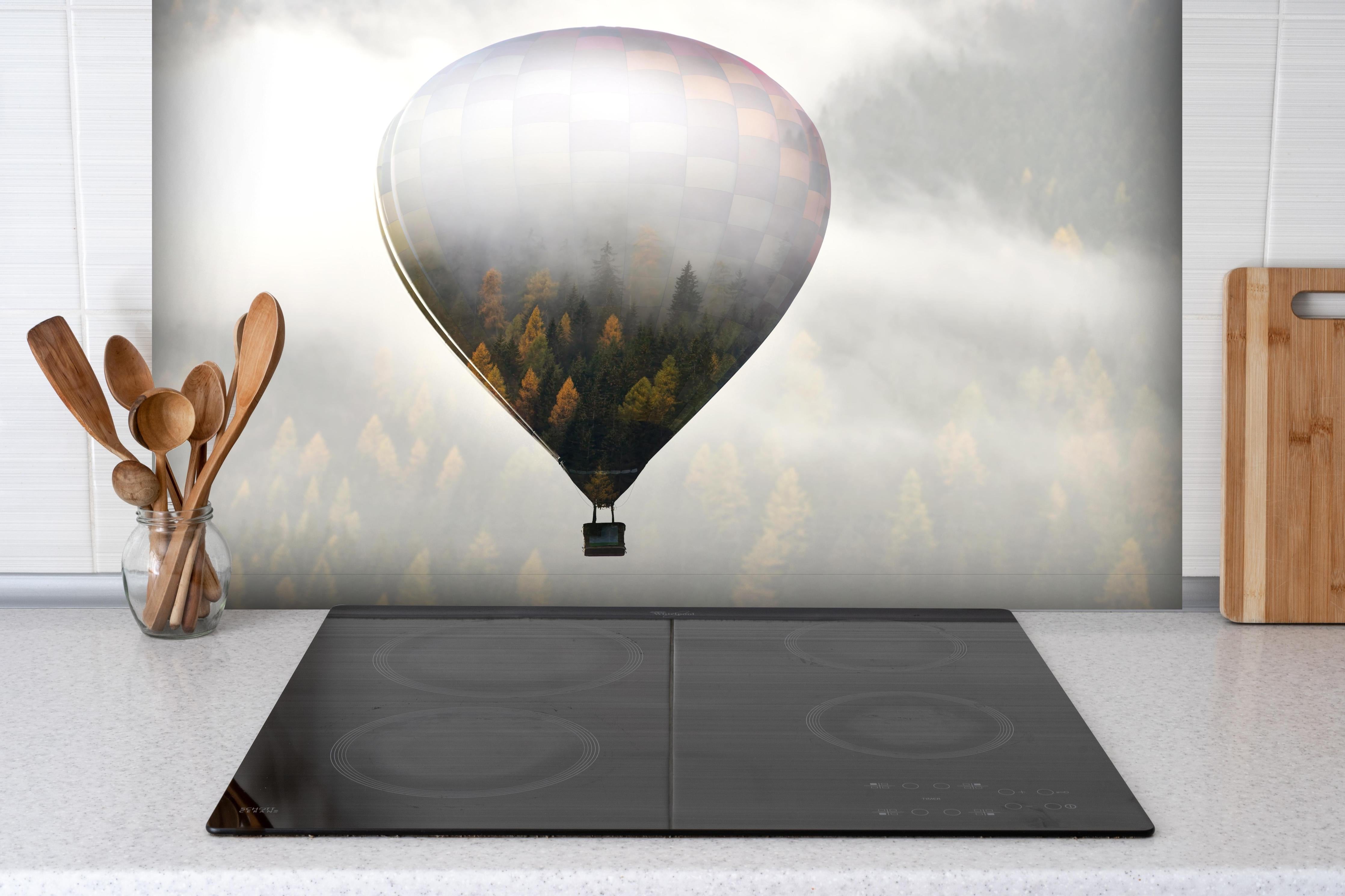 Spritzschutz - Heißluftballon - Spiegelung des Waldes hinter einem Cerankochfeld zwischen Holz-Kochutensilien