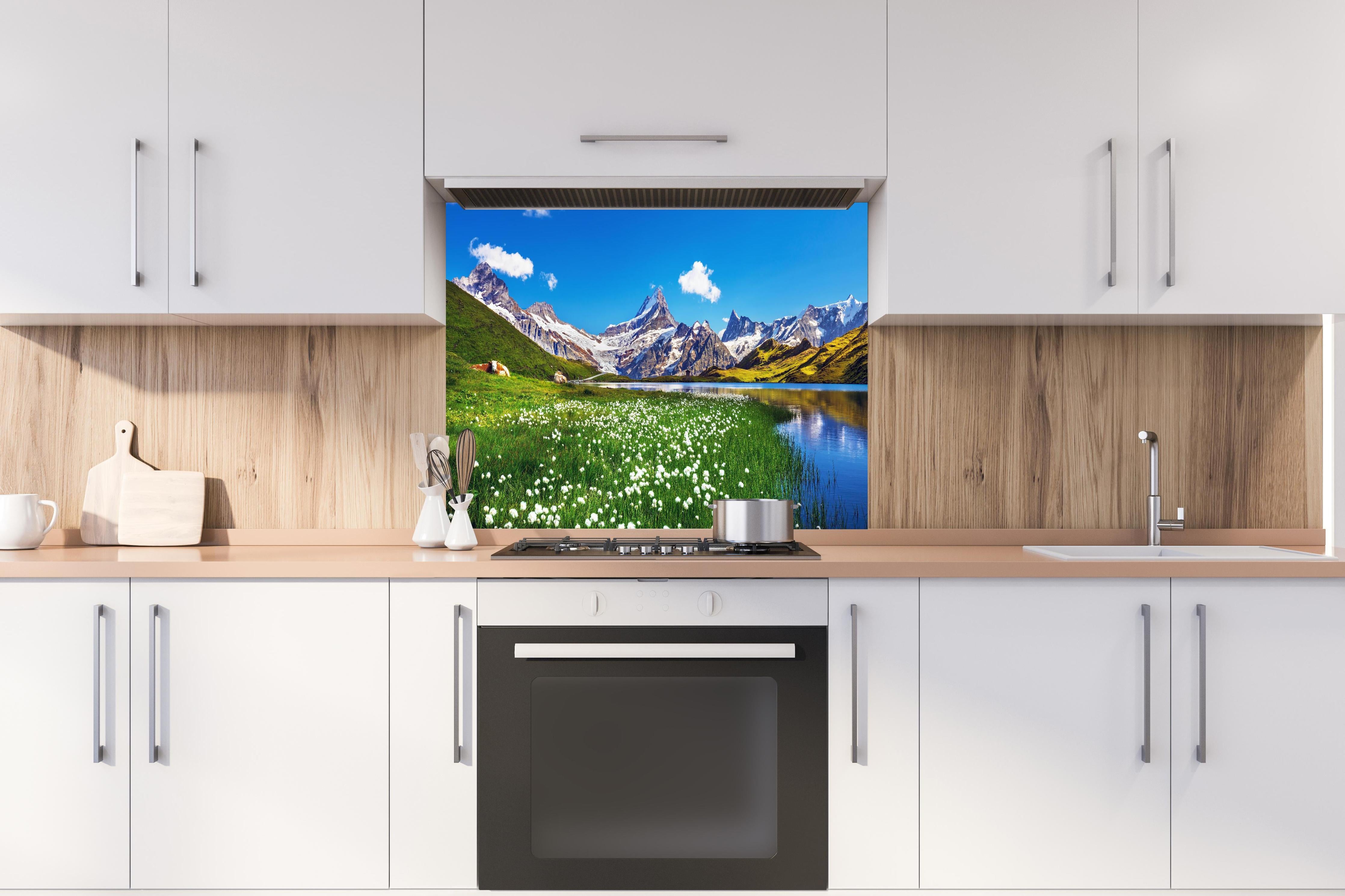 Spritzschutz - Heitere Aussicht auf die Berner Alpenkette hinter einem Cerankochfeld zwischen Holz-Kochutensilien