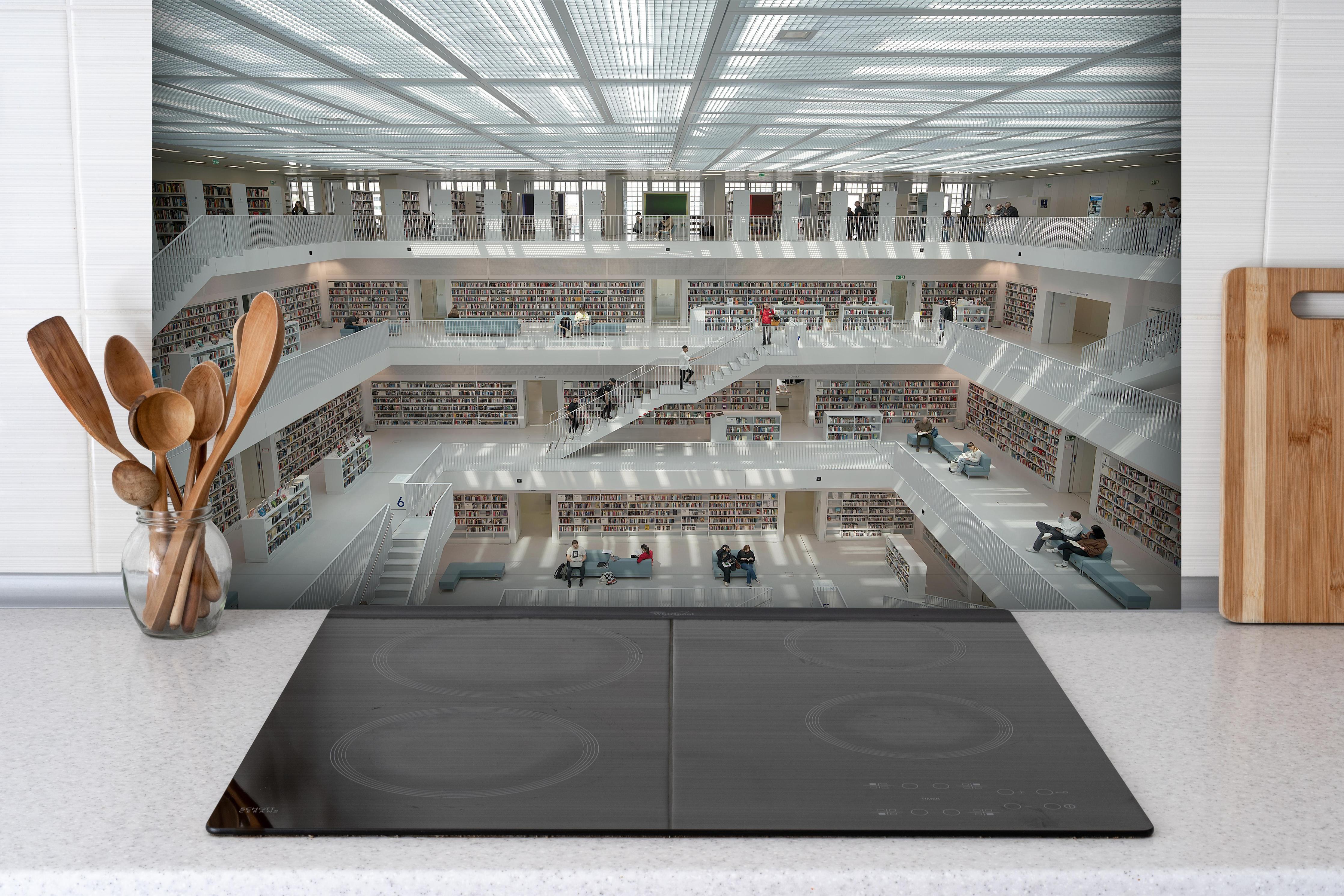 Spritzschutz - Helle Bibliothek in Stuttgart hinter einem Cerankochfeld zwischen Holz-Kochutensilien