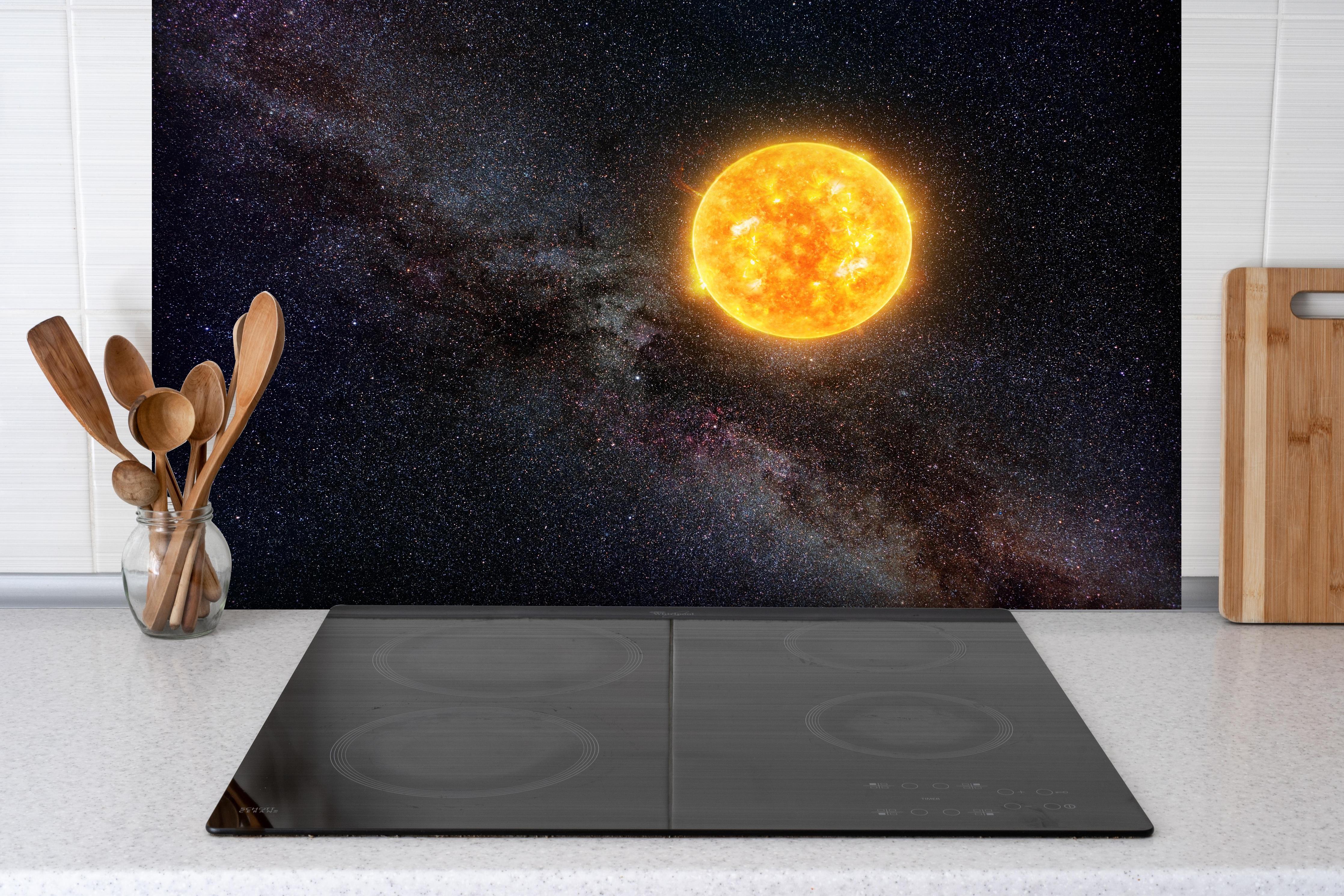 Spritzschutz - Helle Sonne vor dunklem Sternenhimmel hinter einem Cerankochfeld zwischen Holz-Kochutensilien