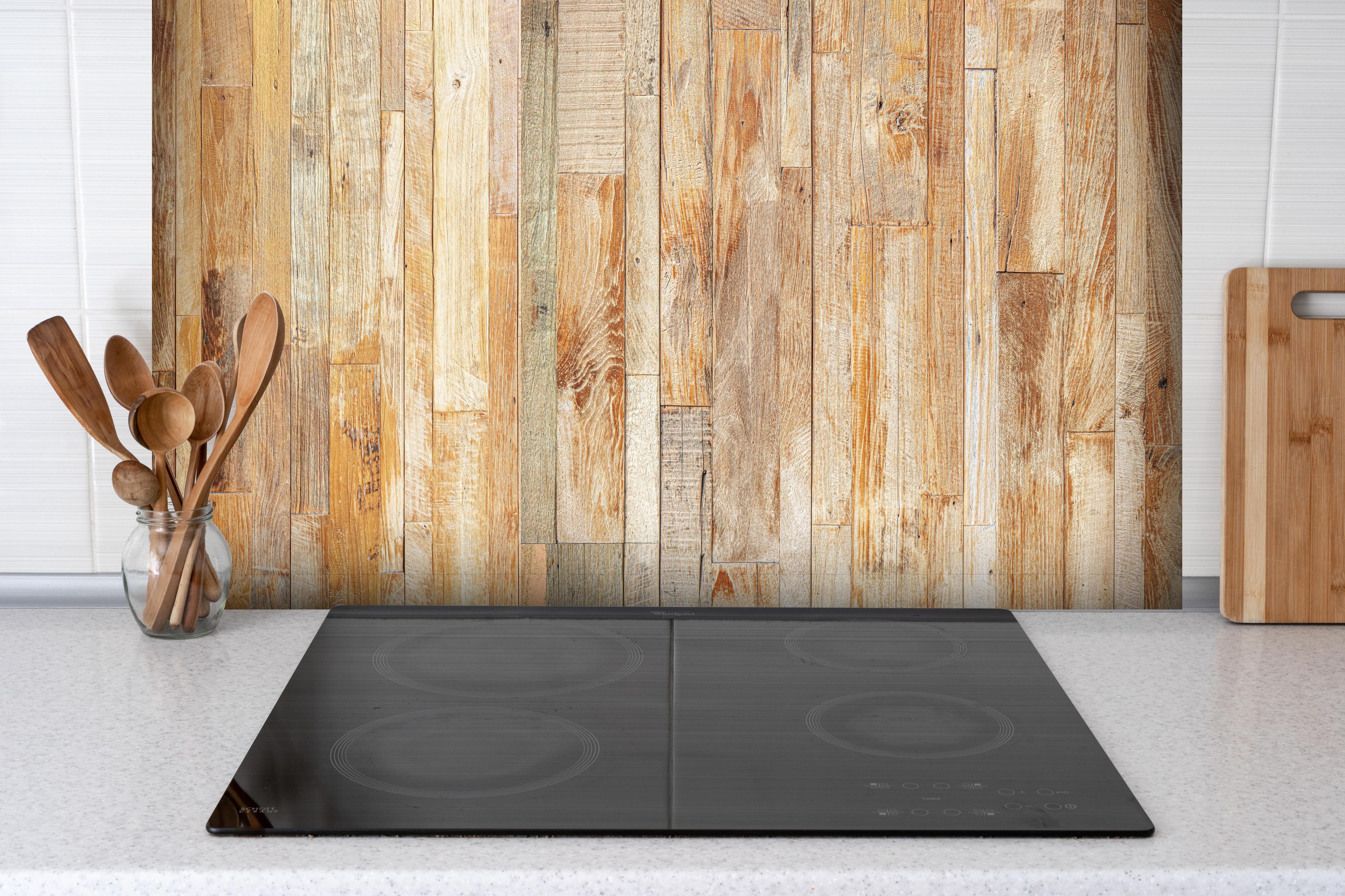 Spritzschutz - Heller Holzhintergrund hinter einem Cerankochfeld zwischen Holz-Kochutensilien