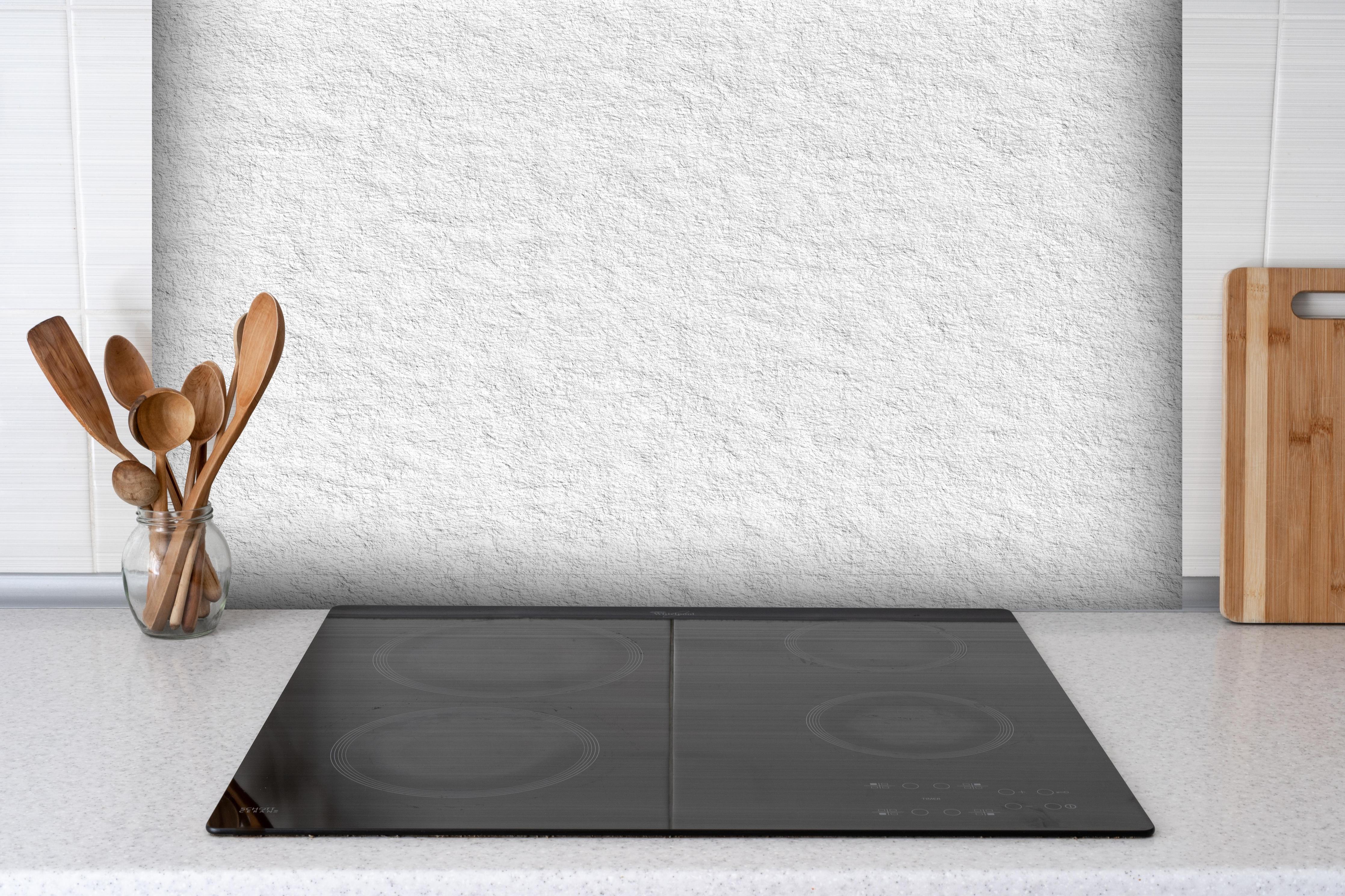 Spritzschutz - Helles Tapeten Muster hinter einem Cerankochfeld zwischen Holz-Kochutensilien