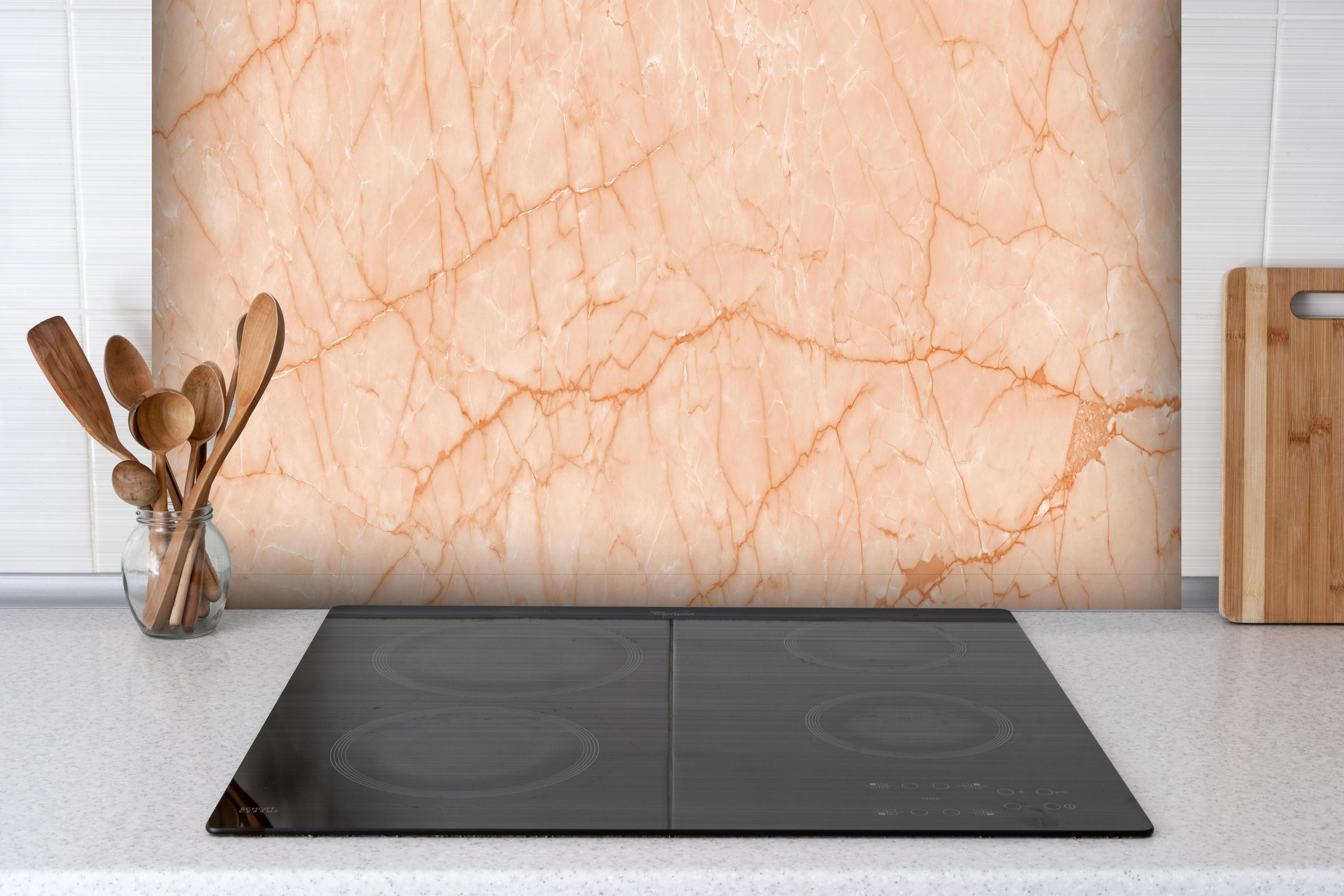 Spritzschutz - Hellrosa Marmor Naturstein hinter einem Cerankochfeld zwischen Holz-Kochutensilien