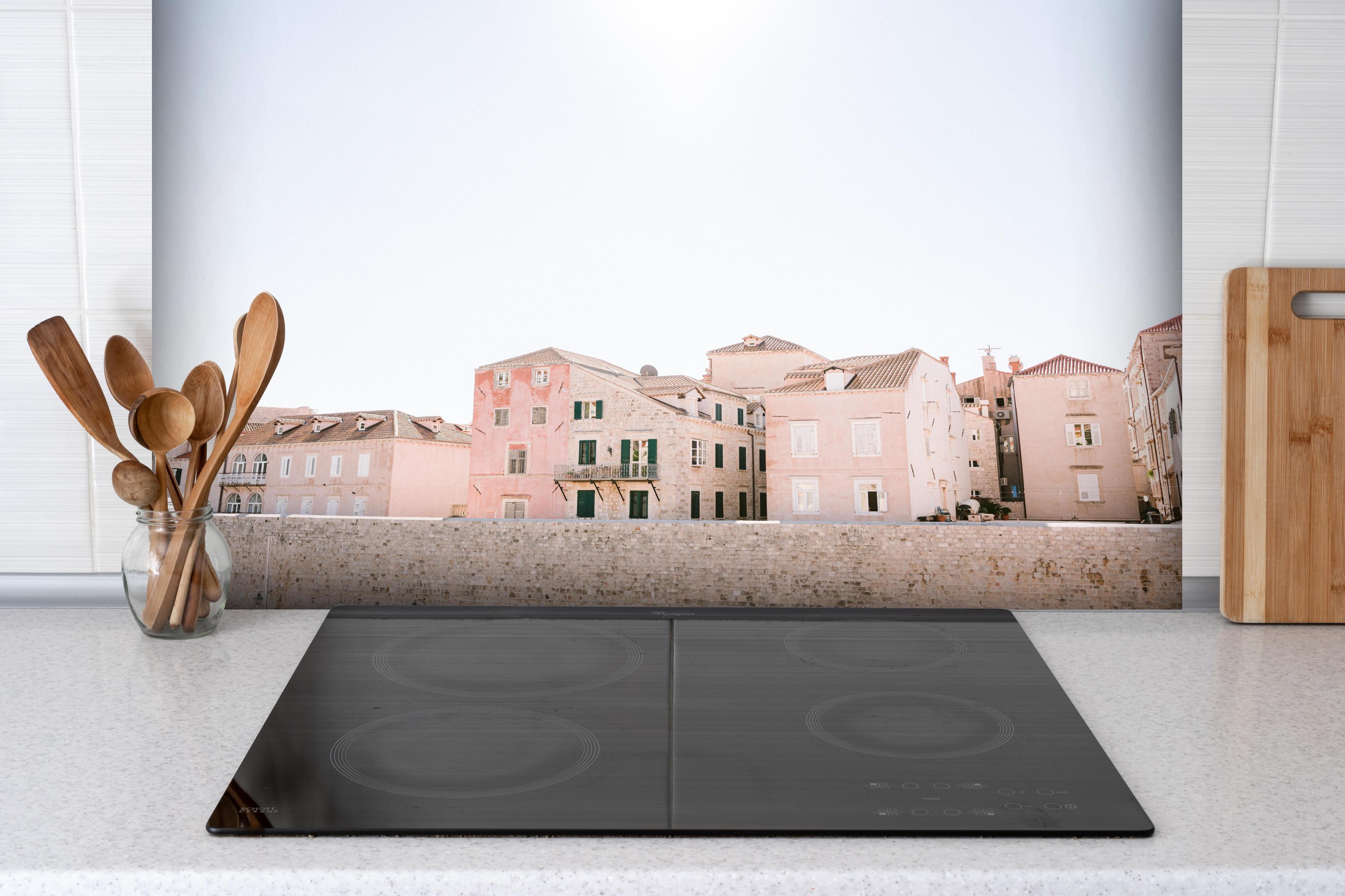 Spritzschutz - Historische Bauten Dubrovnik in Pastell hinter einem Cerankochfeld zwischen Holz-Kochutensilien
