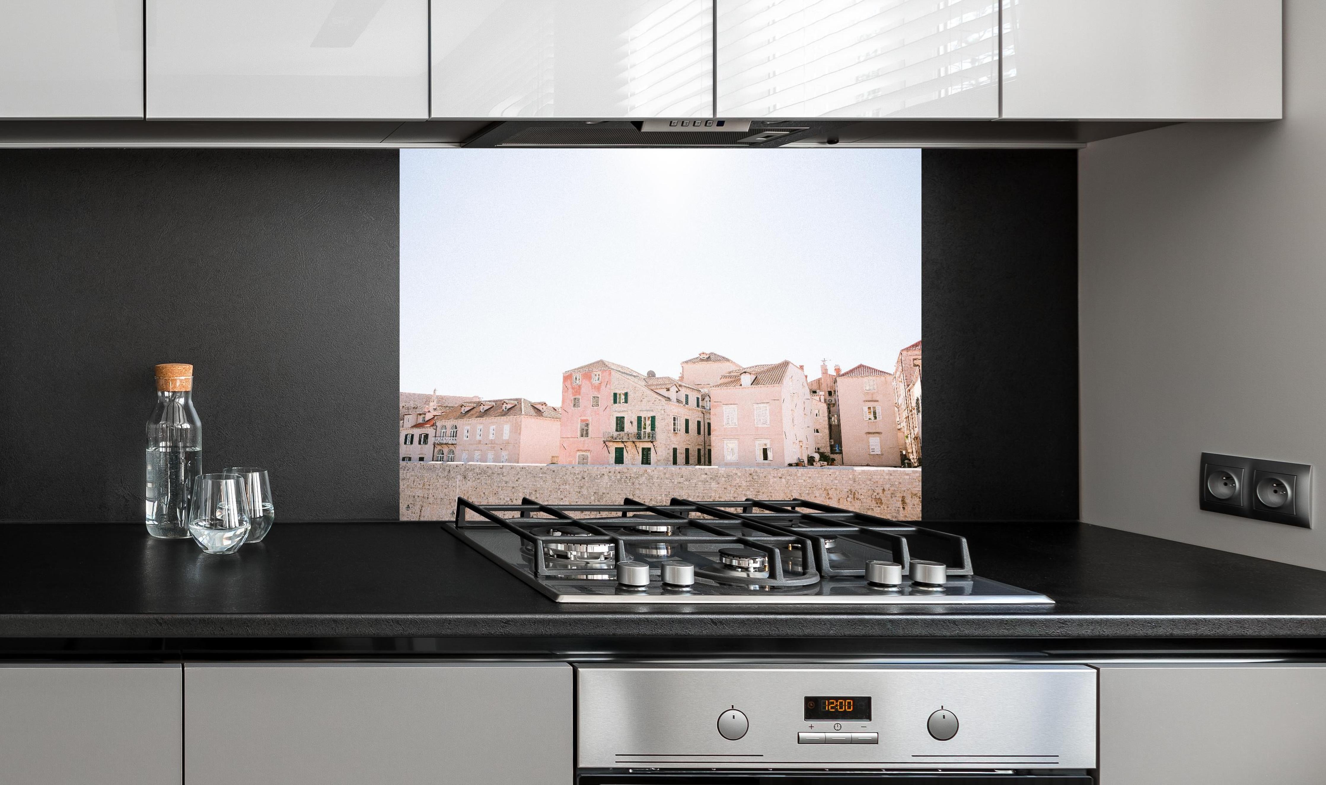 Spritzschutz - Historische Bauten Dubrovnik in Pastell hinter einem Cerankochfeld zwischen Holz-Kochutensilien