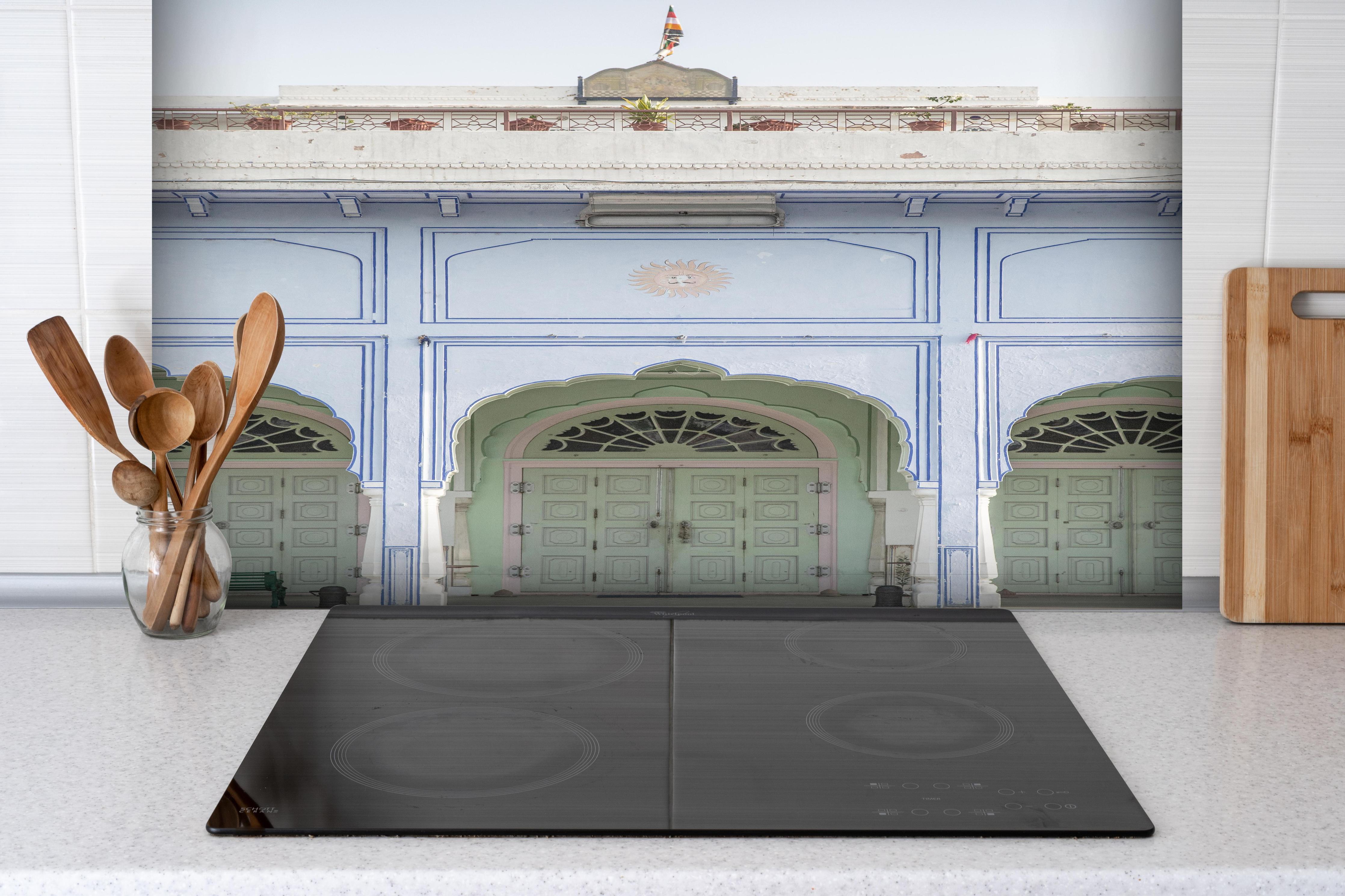 Spritzschutz - Historischer Palast - Eingang hinter einem Cerankochfeld zwischen Holz-Kochutensilien