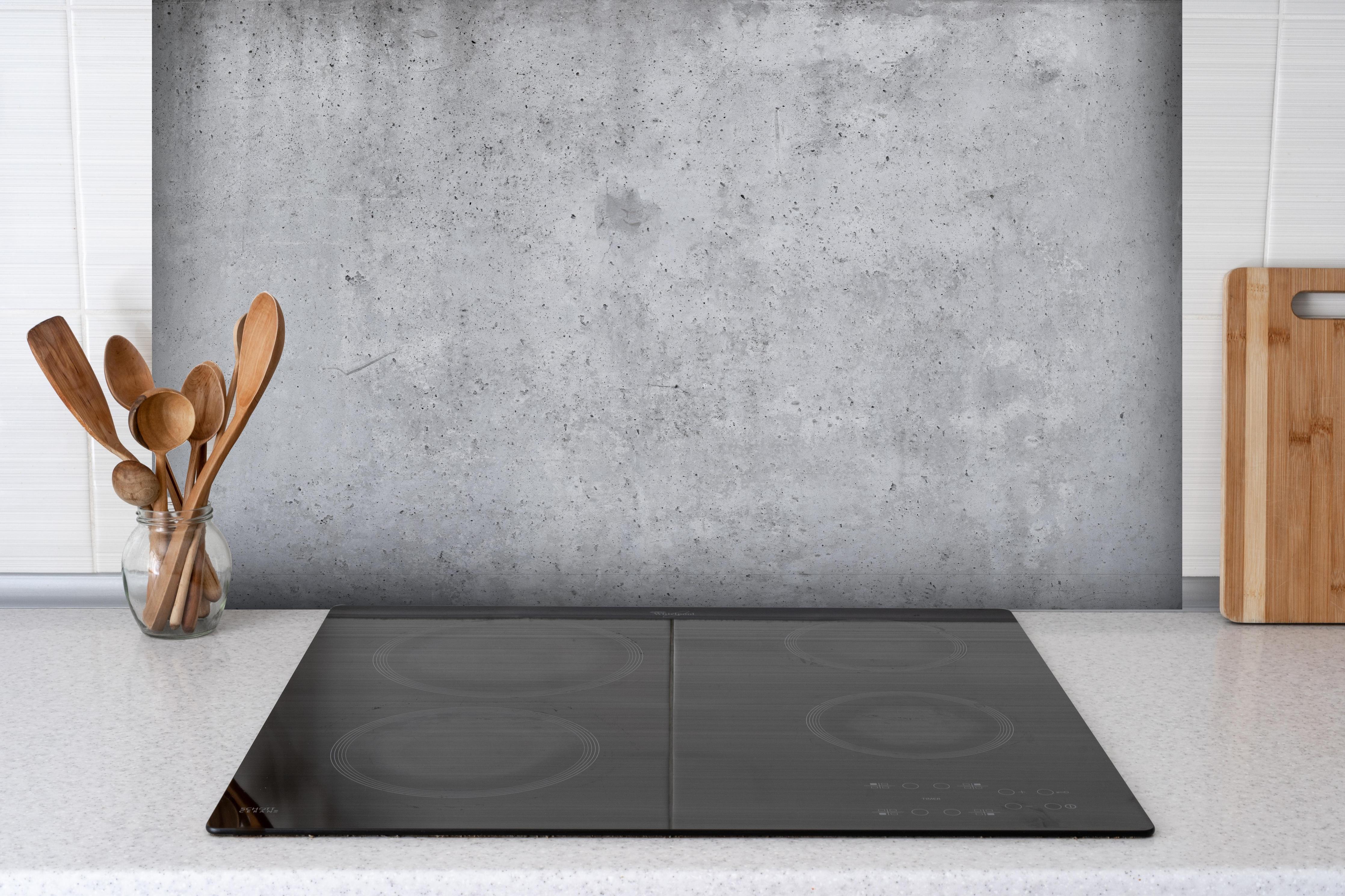 Spritzschutz - Hochauflösende Beton-Tapete hinter einem Cerankochfeld zwischen Holz-Kochutensilien