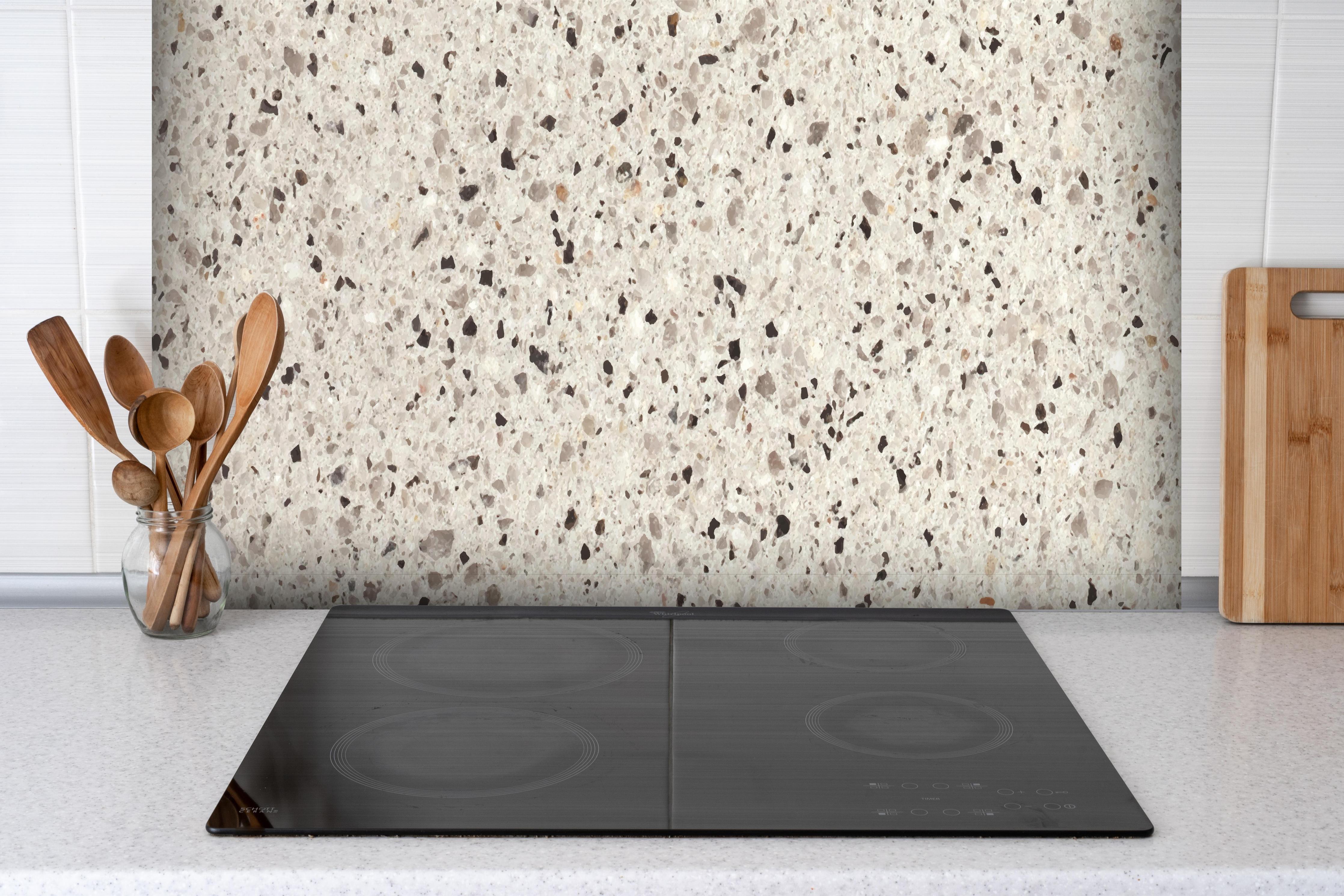Spritzschutz - Hochwertige Weiß-und-Grau Terrazzo Textur hinter einem Cerankochfeld zwischen Holz-Kochutensilien