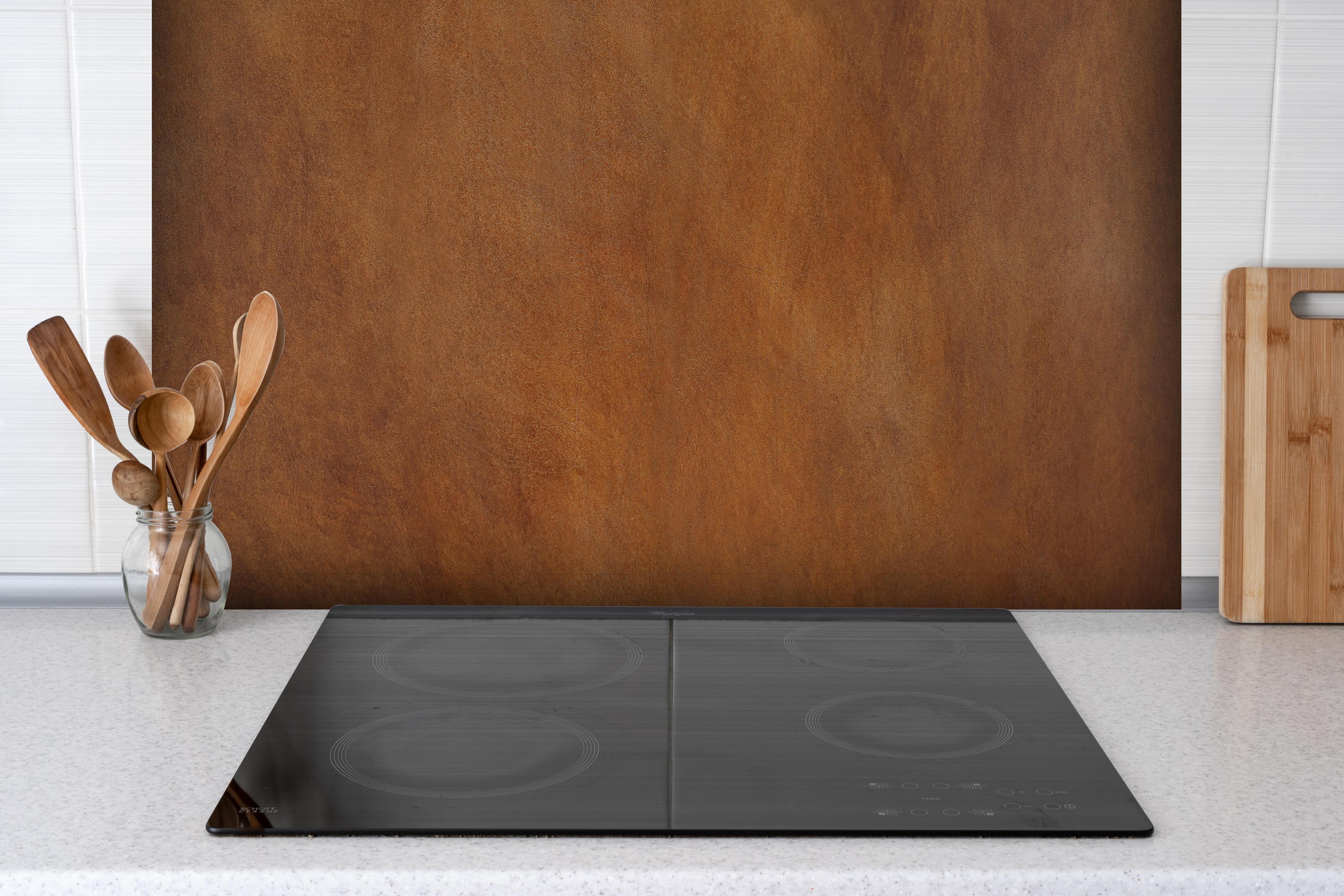 Spritzschutz - Hochwertige abstrakte braune Lederoberfläche hinter einem Cerankochfeld zwischen Holz-Kochutensilien
