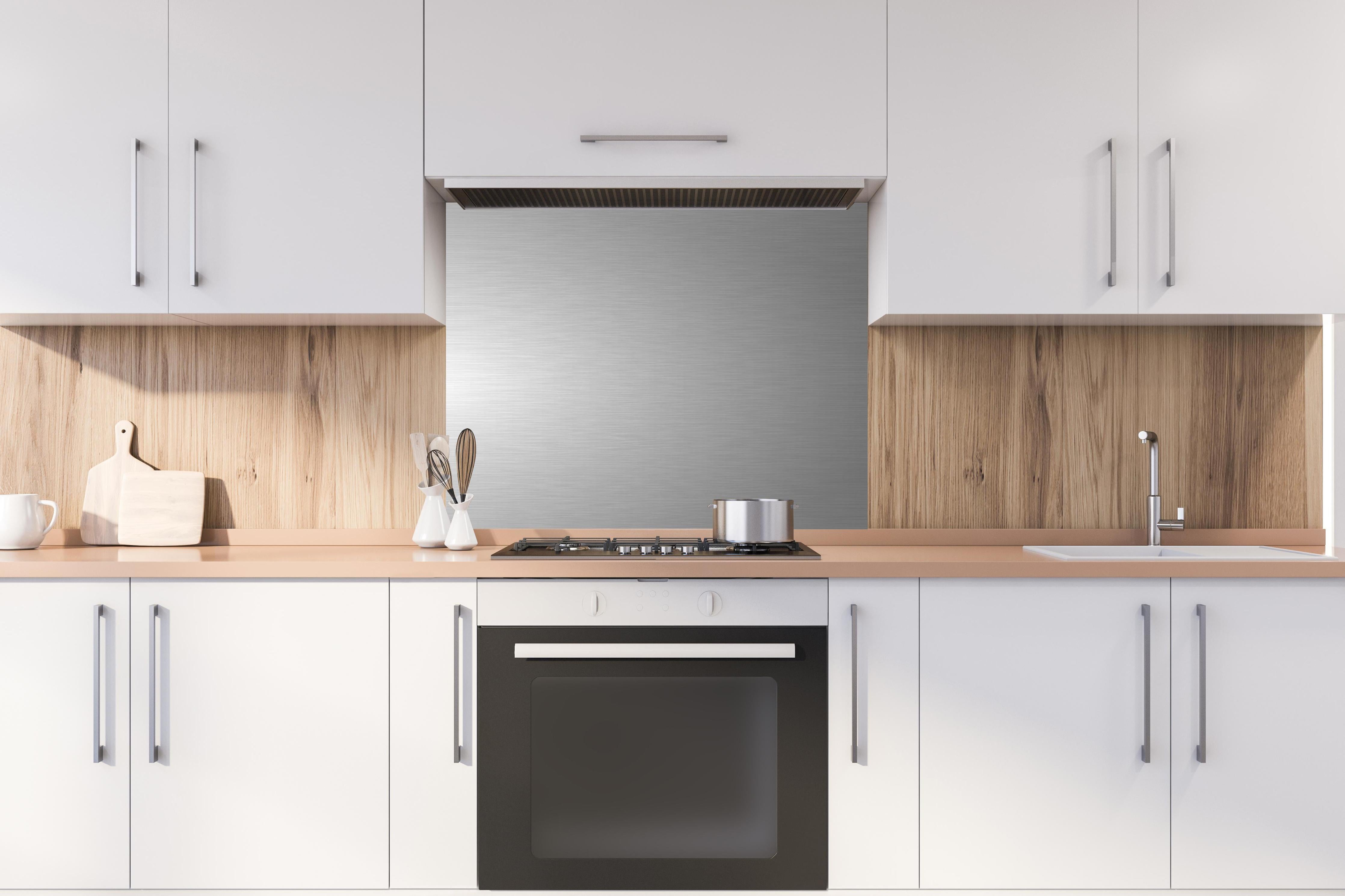 Spritzschutz - Hochwertige gebürstete Silber-Metallstruktur hinter einem Cerankochfeld zwischen Holz-Kochutensilien