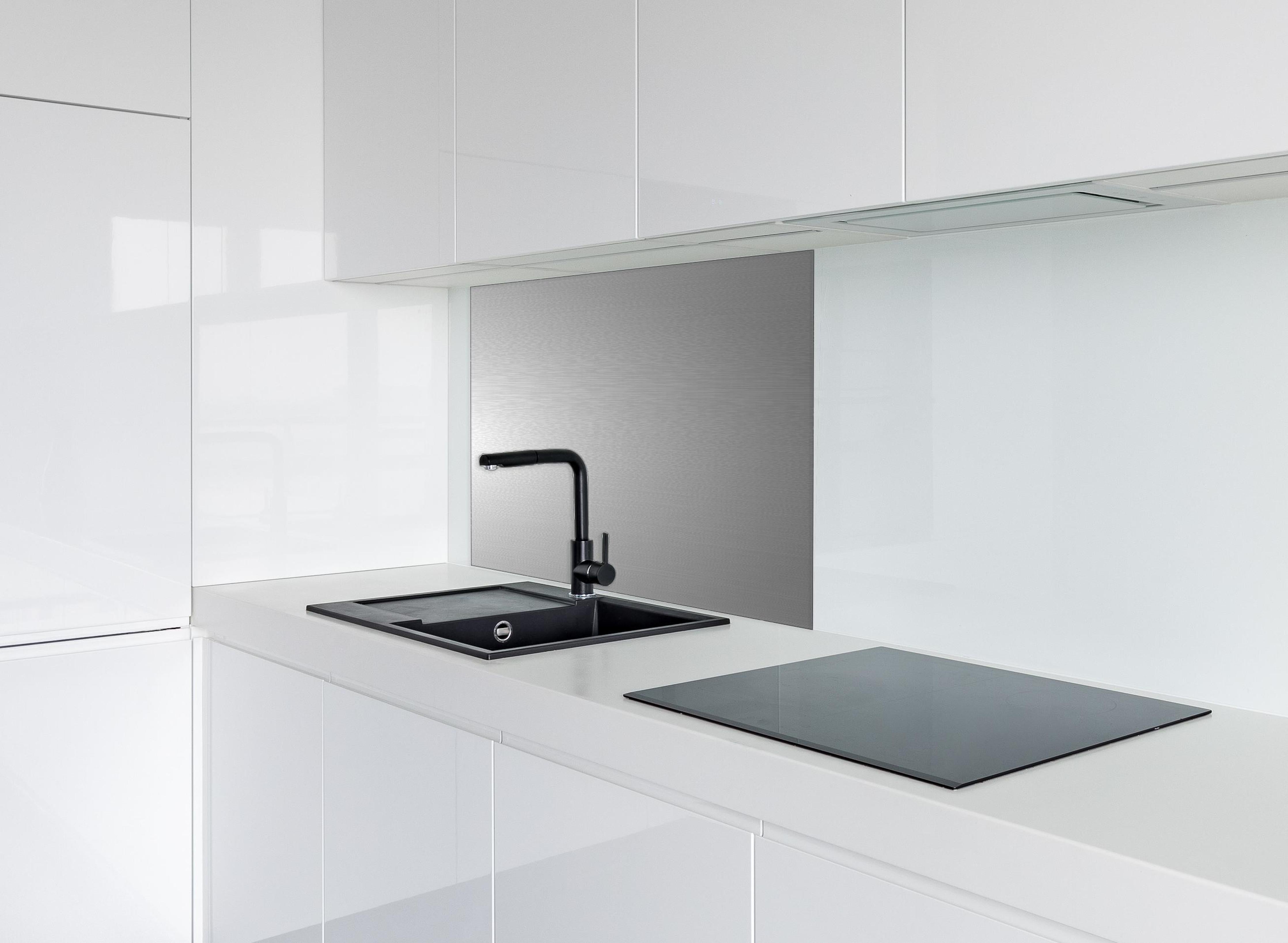 Spritzschutz - Hochwertige gebürstete Silber-Metallstruktur hinter einem Cerankochfeld zwischen Holz-Kochutensilien