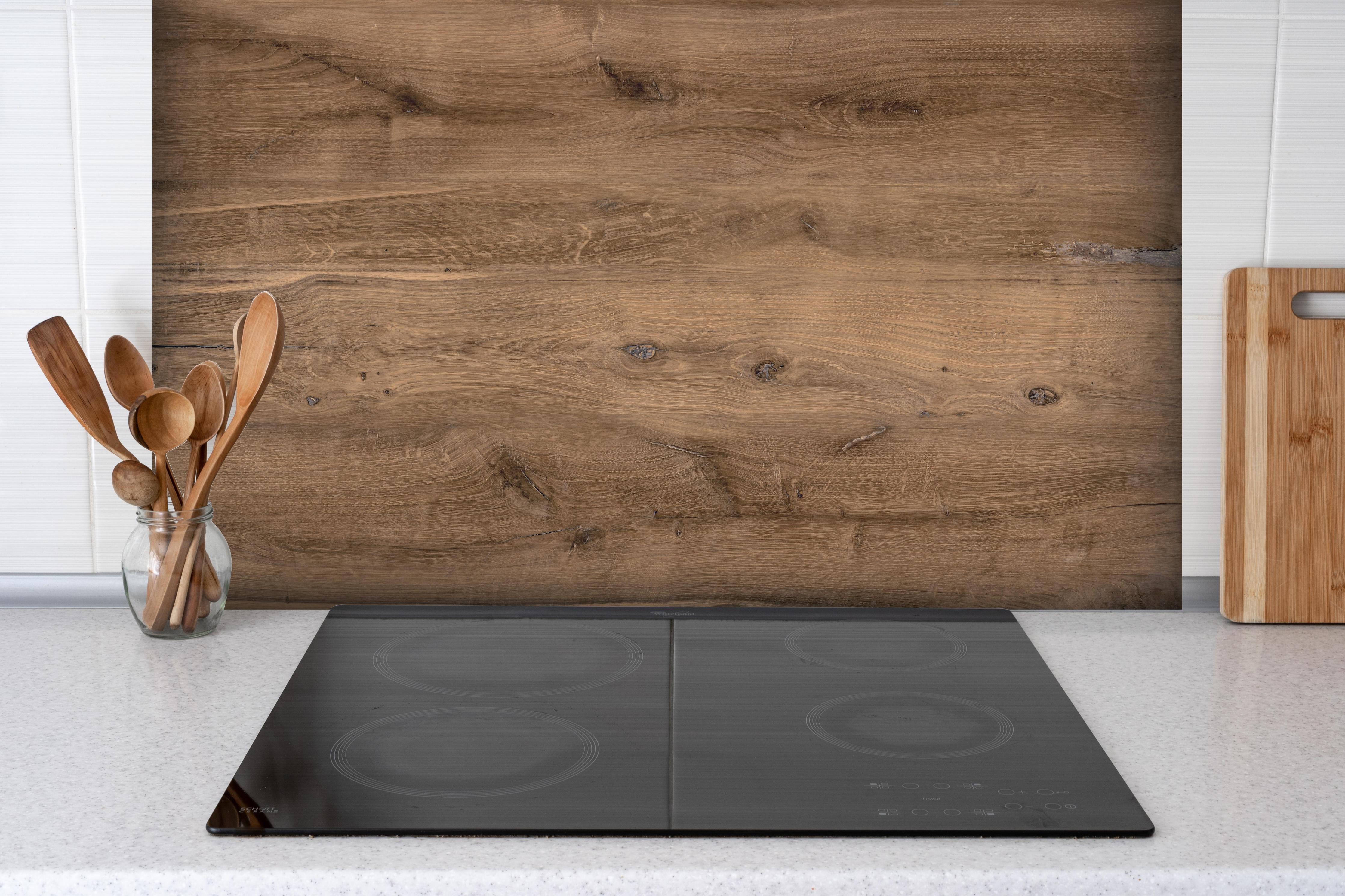 Spritzschutz - Hölzernes Eichenholz-Brett hinter einem Cerankochfeld zwischen Holz-Kochutensilien