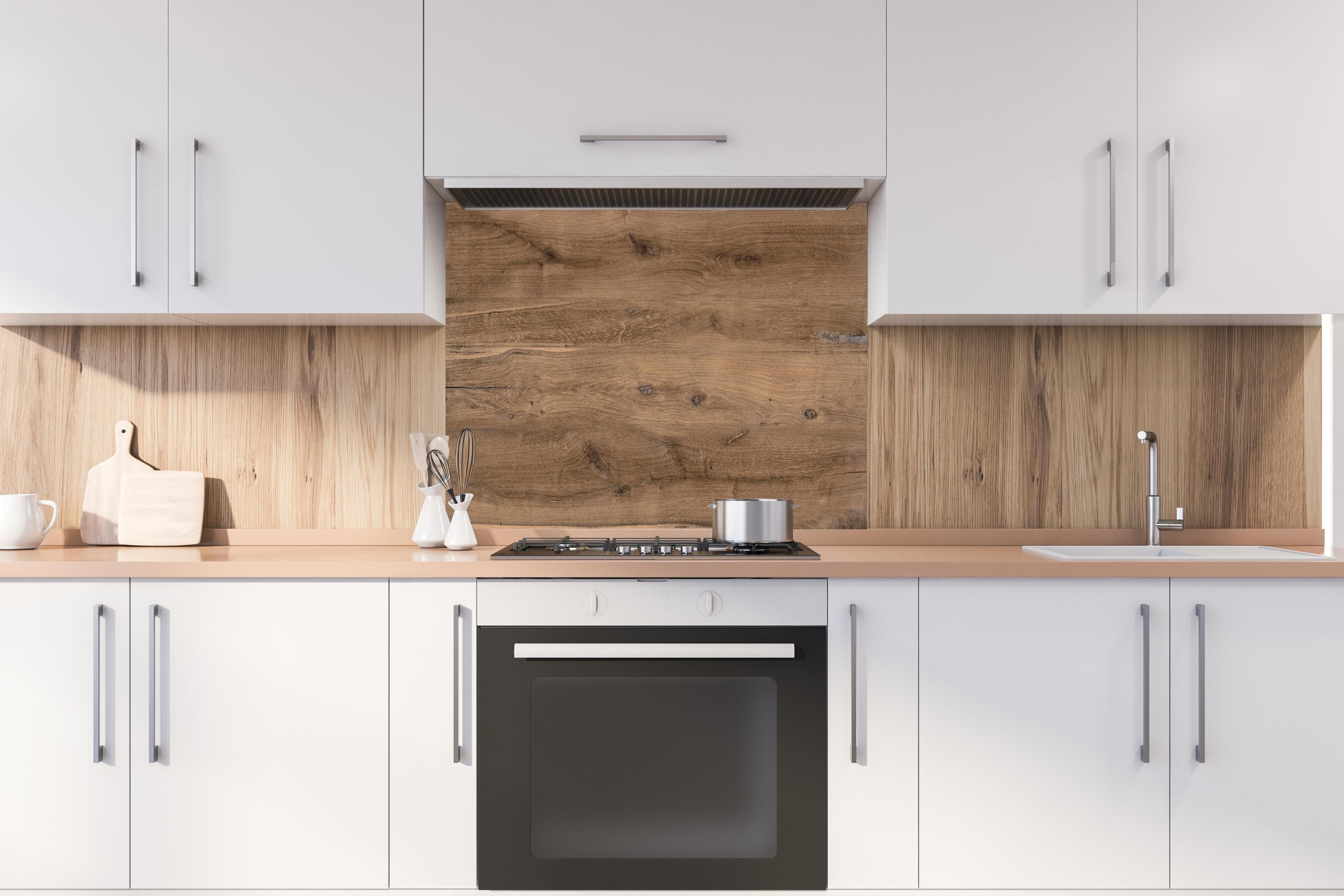 Spritzschutz - Hölzernes Eichenholz-Brett hinter einem Cerankochfeld zwischen Holz-Kochutensilien