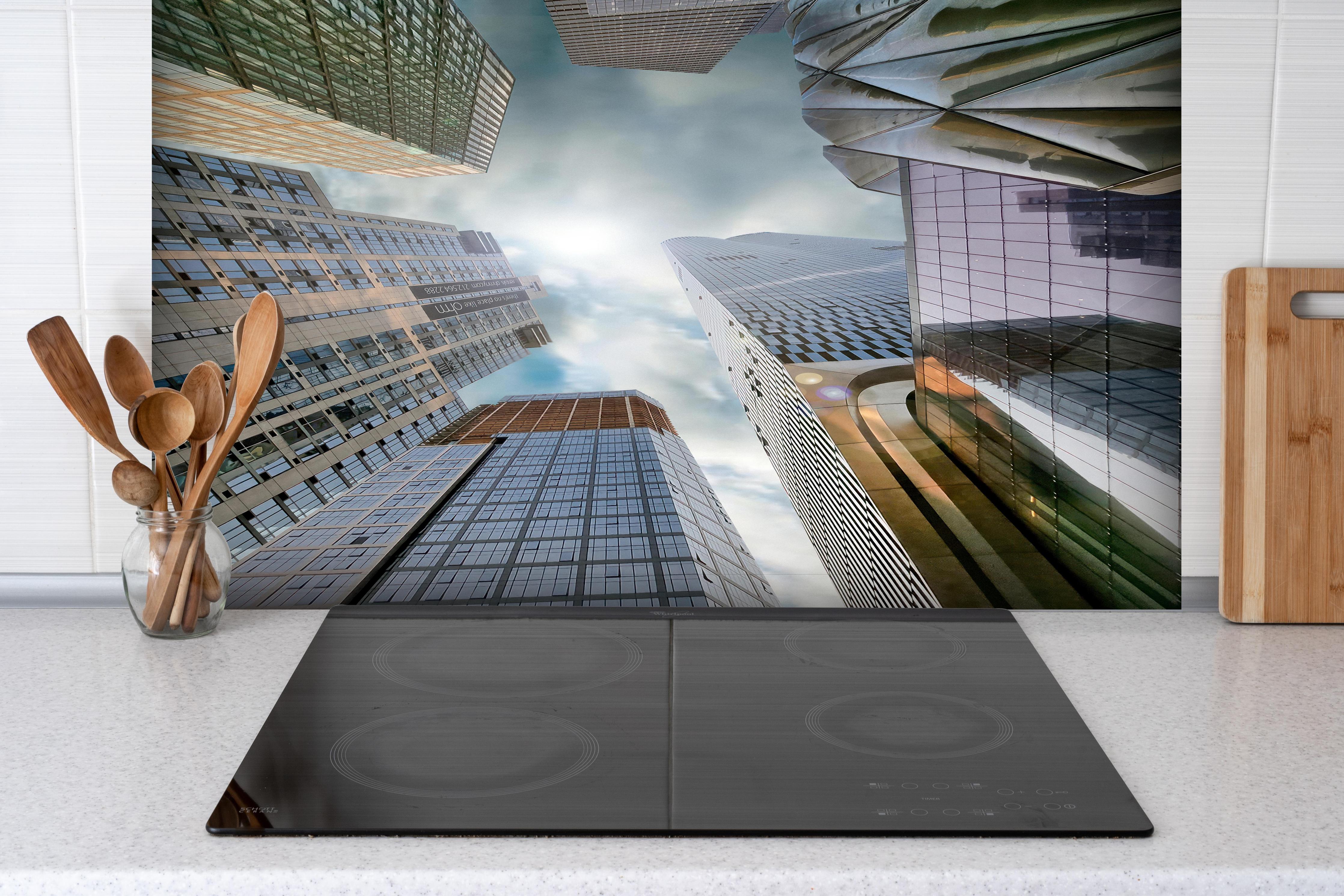 Spritzschutz - Hohe Gebäude - Menschen Perspektive hinter einem Cerankochfeld zwischen Holz-Kochutensilien