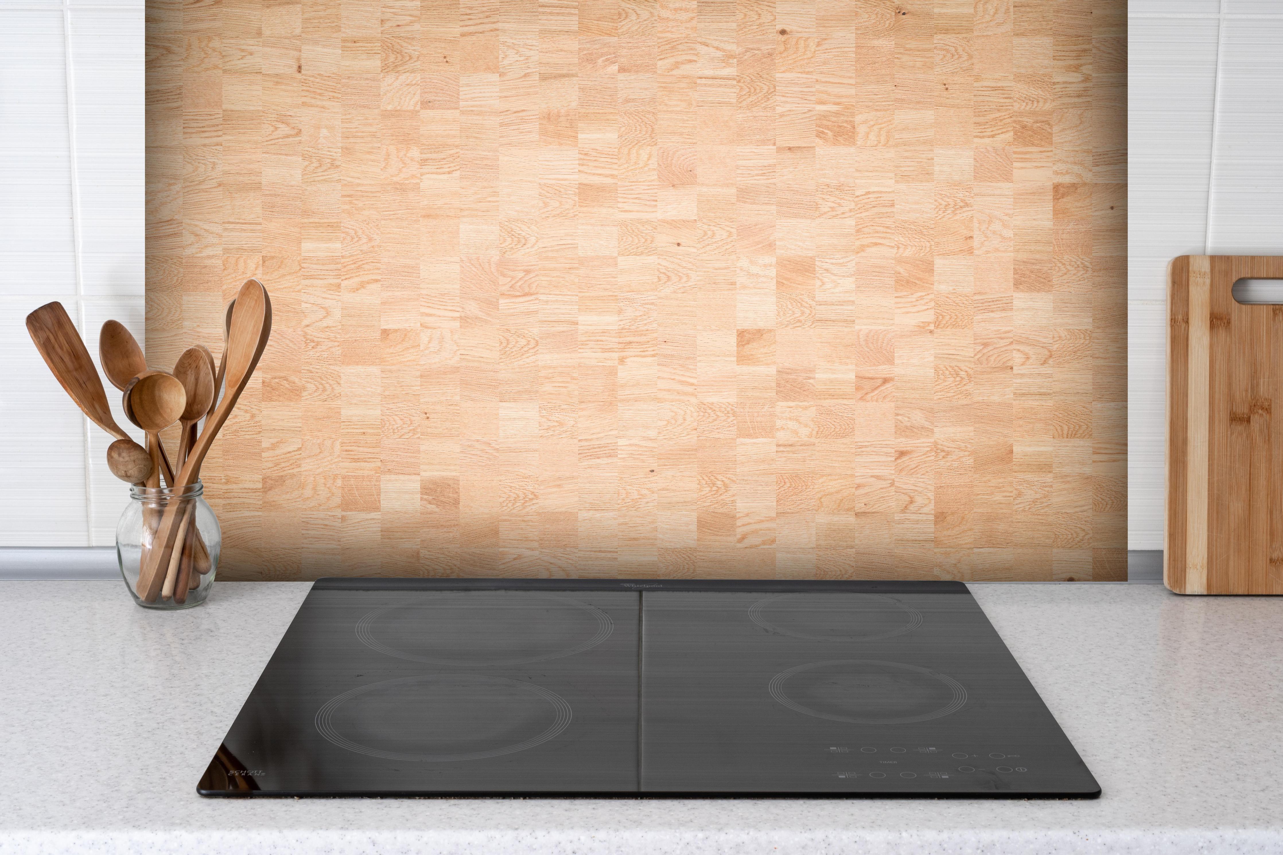 Spritzschutz - Holztextur aus Eschenholz hinter einem Cerankochfeld zwischen Holz-Kochutensilien