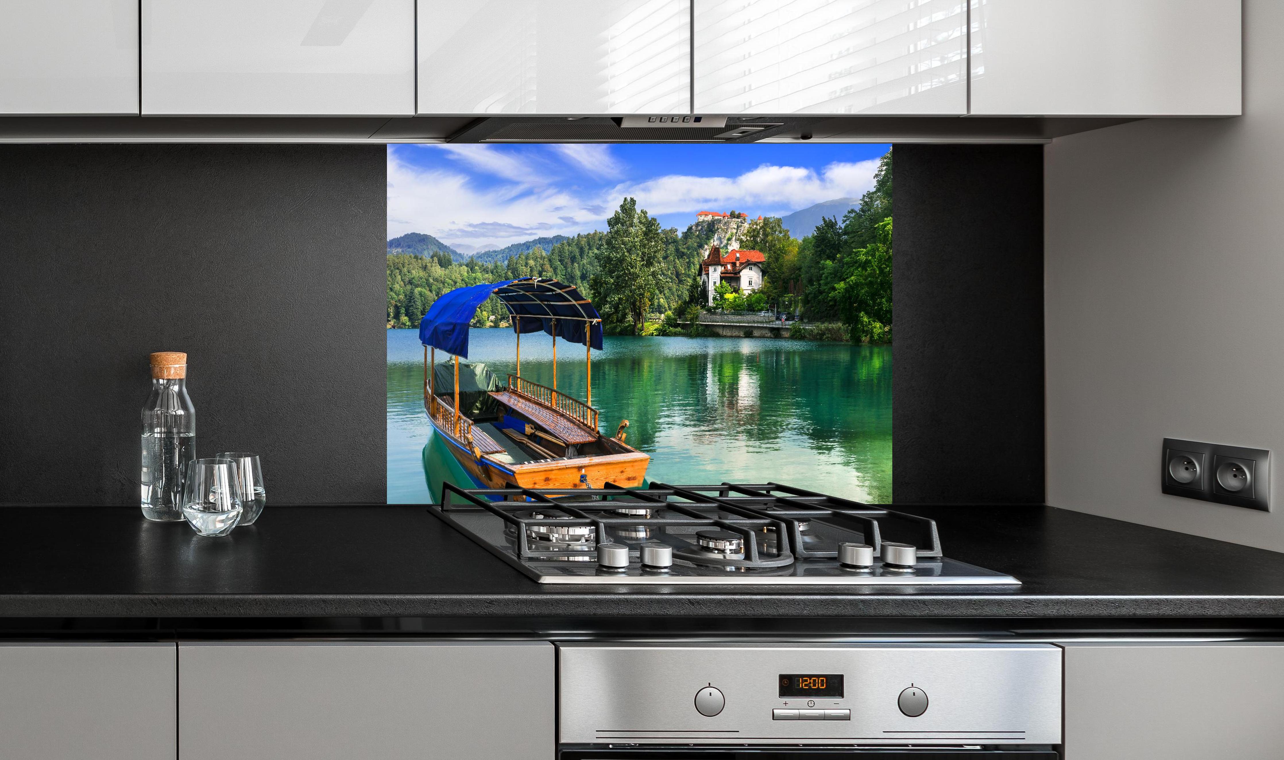 Spritzschutz - Idyllischer Bled See, Holzboot, Slowenien hinter einem Cerankochfeld zwischen Holz-Kochutensilien