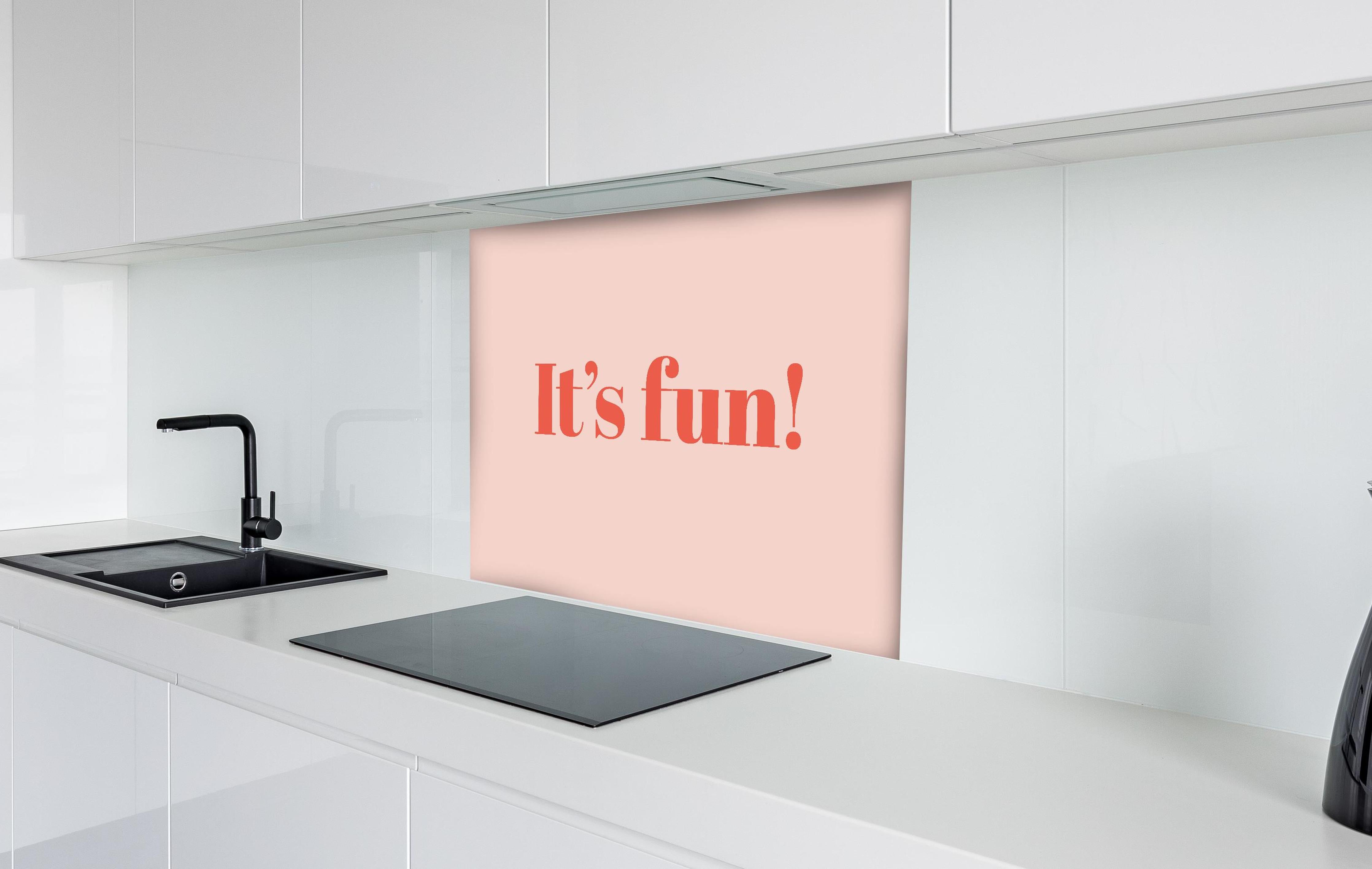 Spritzschutz - Inspirierender 'It's Fun!' Typo-Print in Pink hinter einem Cerankochfeld zwischen Holz-Kochutensilien