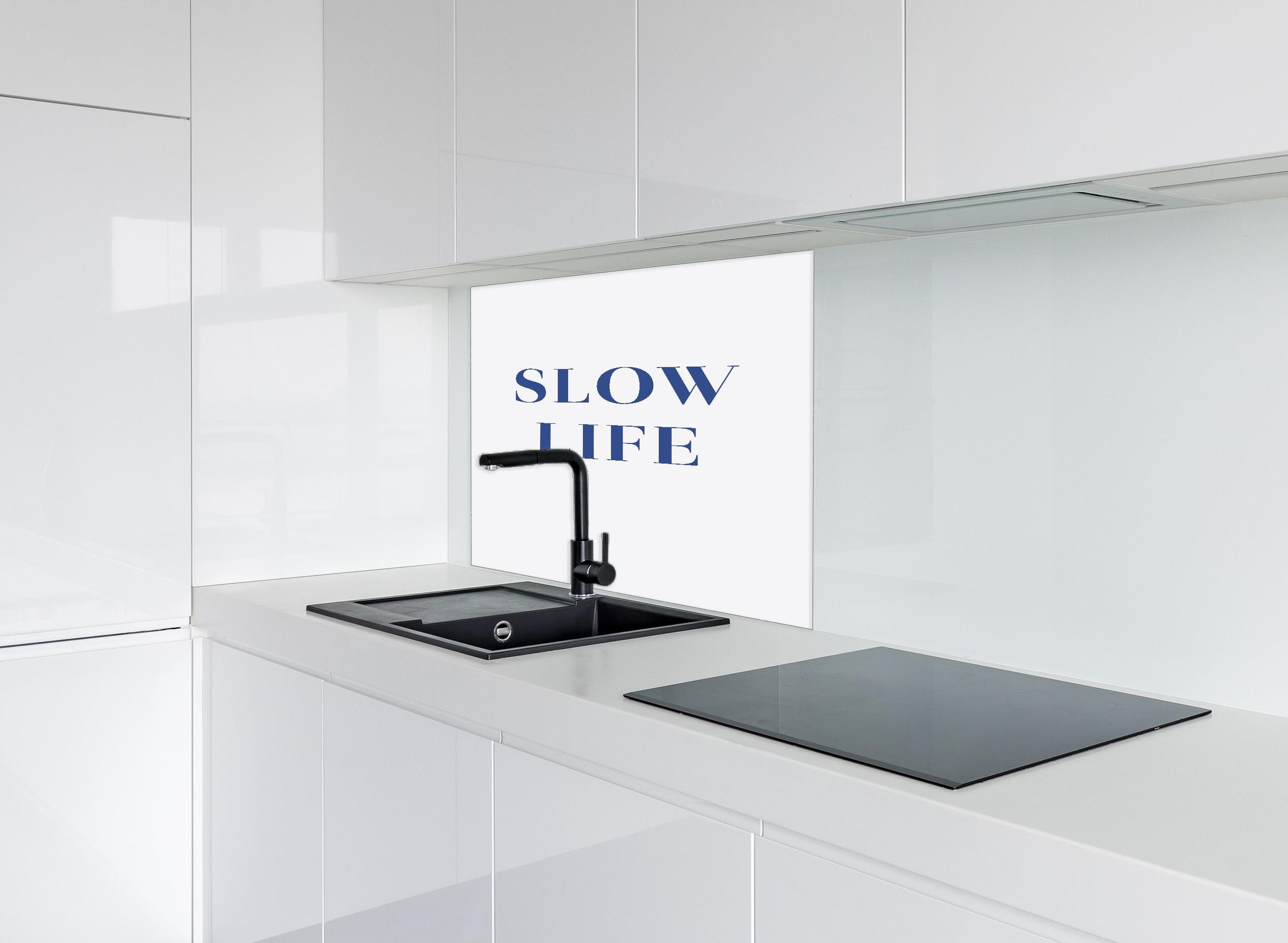 Spritzschutz - Inspirierendes Slow Life Zitat, Blau auf Weiß hinter einem Cerankochfeld zwischen Holz-Kochutensilien