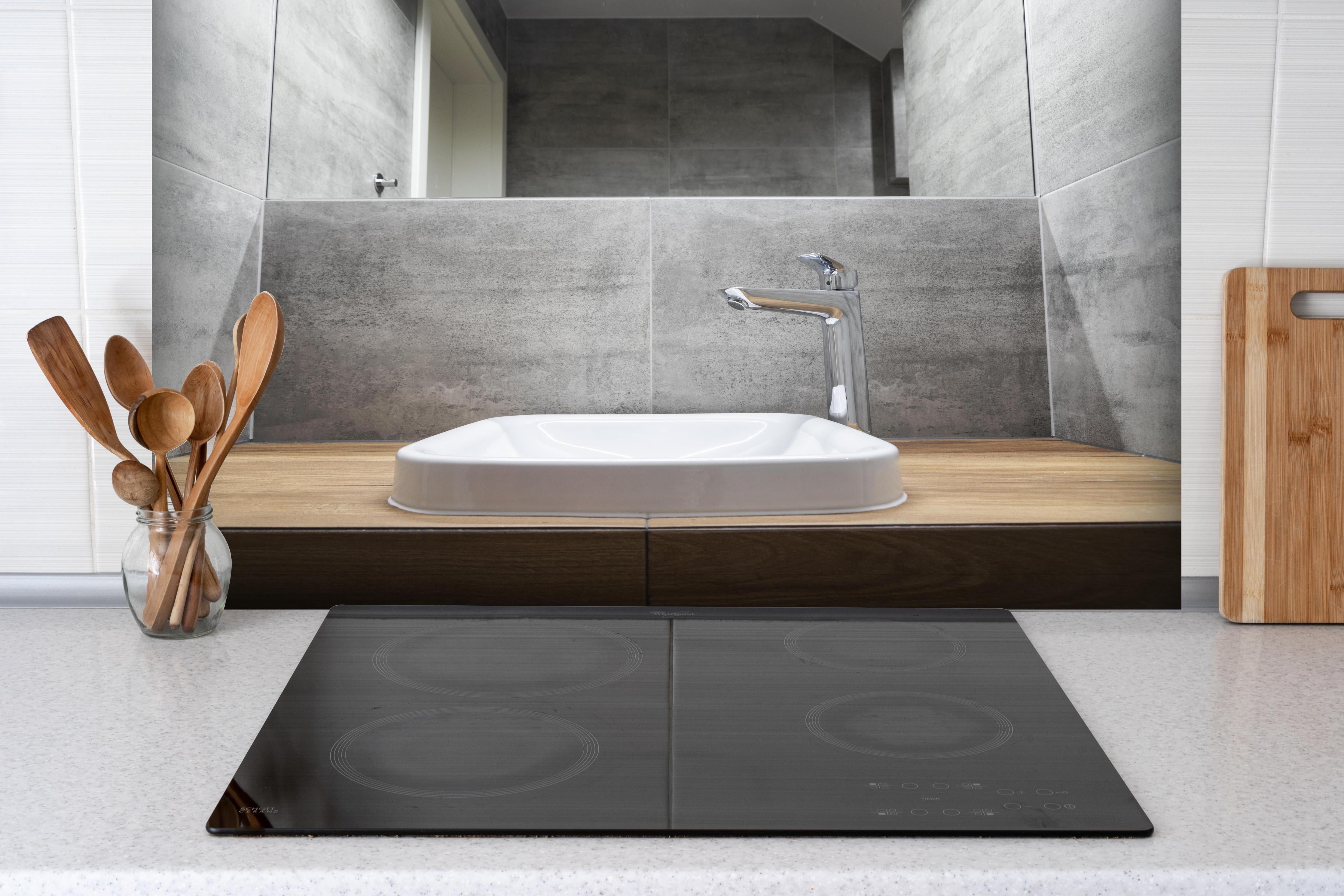 Spritzschutz - Interieur eines modernen Badezimmers hinter einem Cerankochfeld zwischen Holz-Kochutensilien