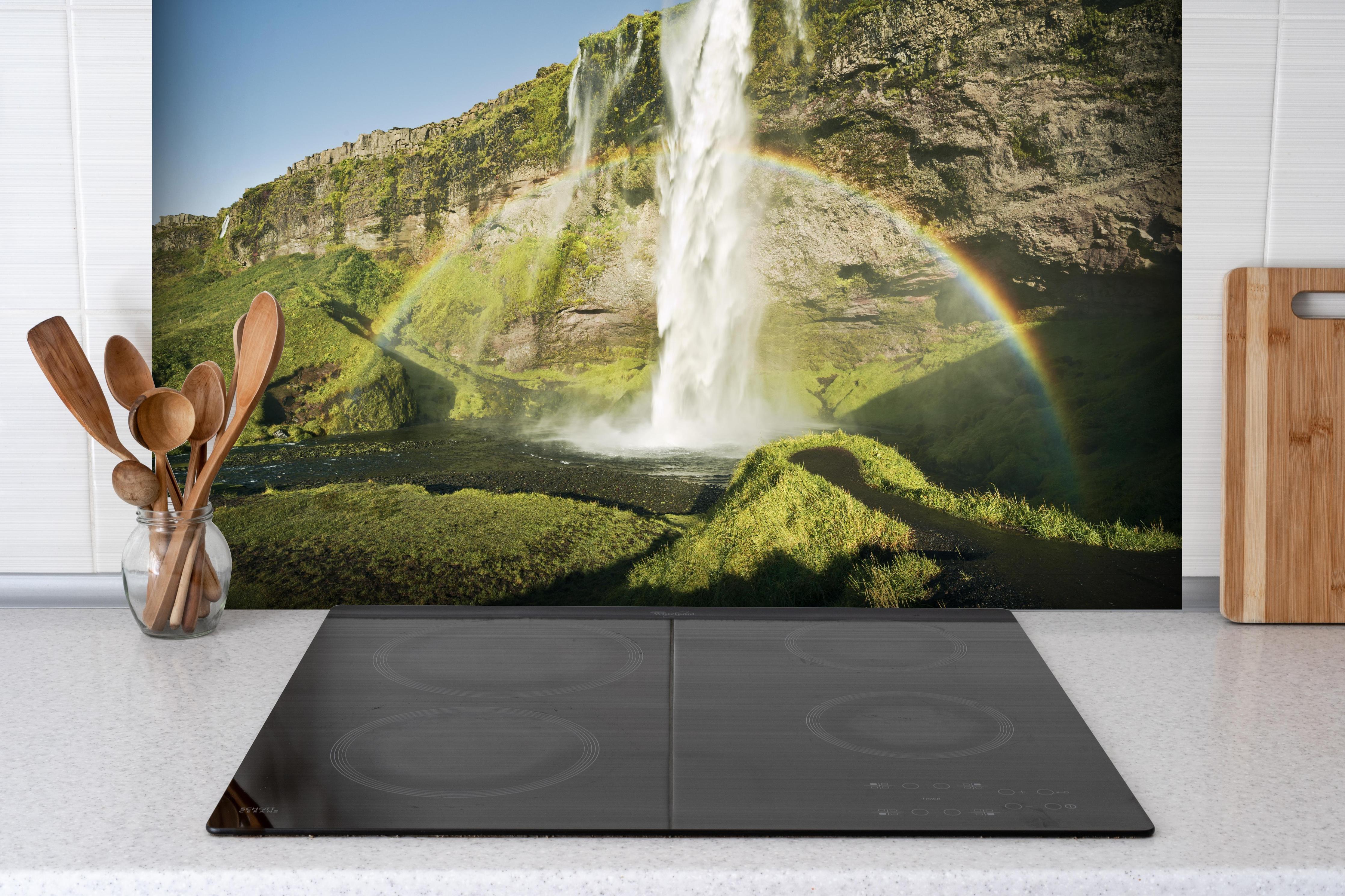Spritzschutz - Island Wasserfall Regenbogen Naturschauspiel hinter einem Cerankochfeld zwischen Holz-Kochutensilien