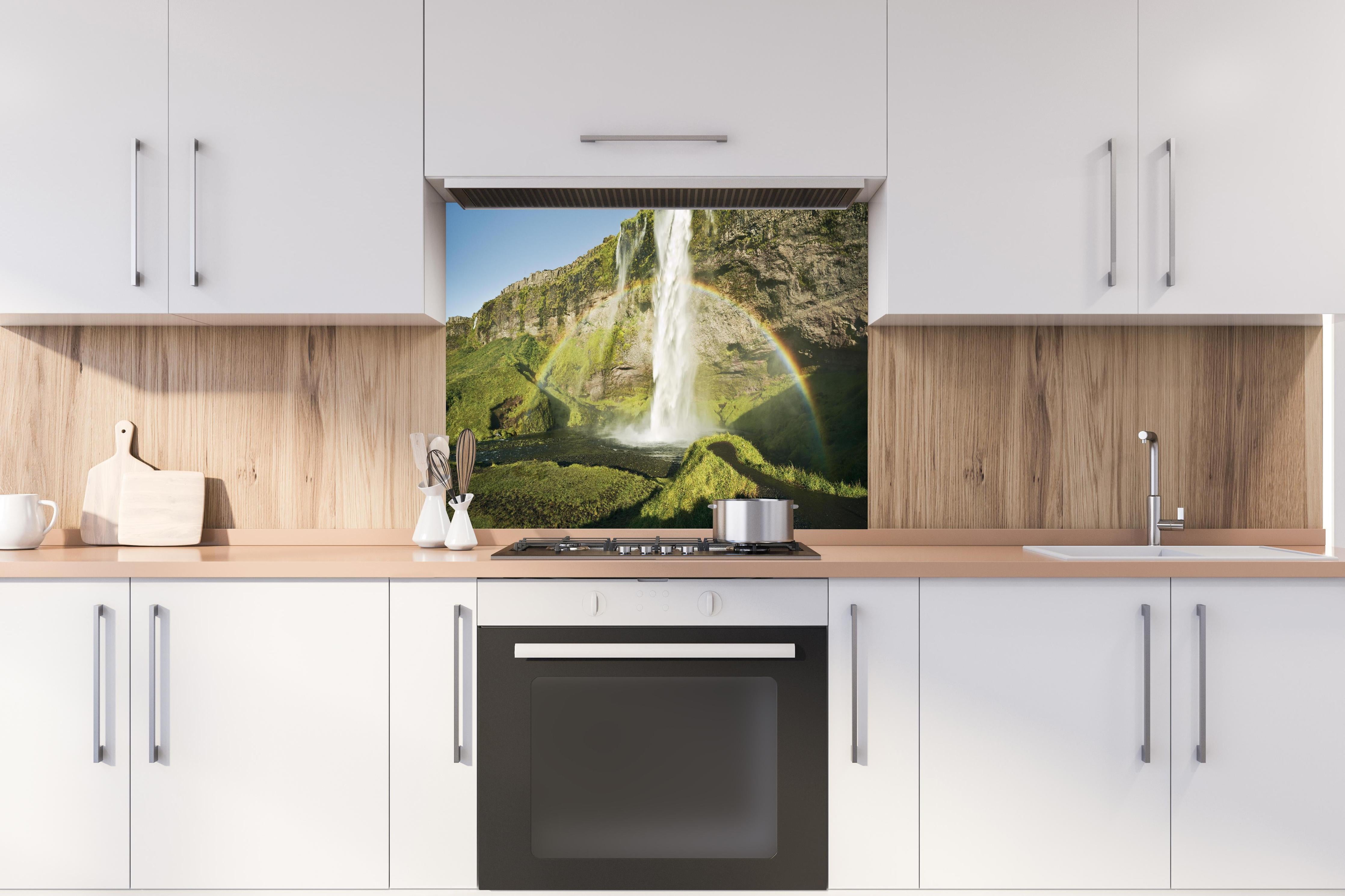 Spritzschutz - Island Wasserfall Regenbogen Naturschauspiel hinter einem Cerankochfeld zwischen Holz-Kochutensilien