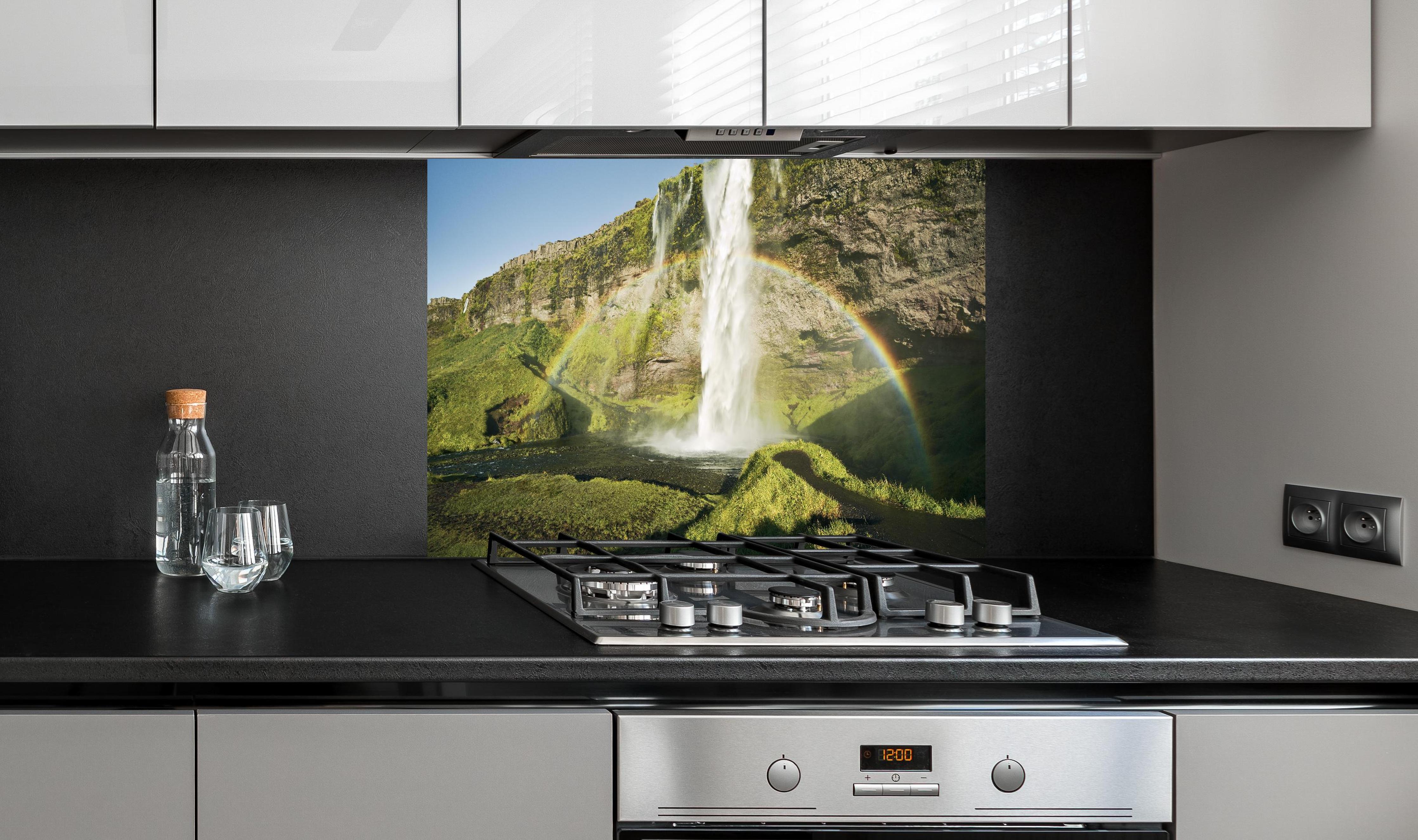 Spritzschutz - Island Wasserfall Regenbogen Naturschauspiel hinter einem Cerankochfeld zwischen Holz-Kochutensilien