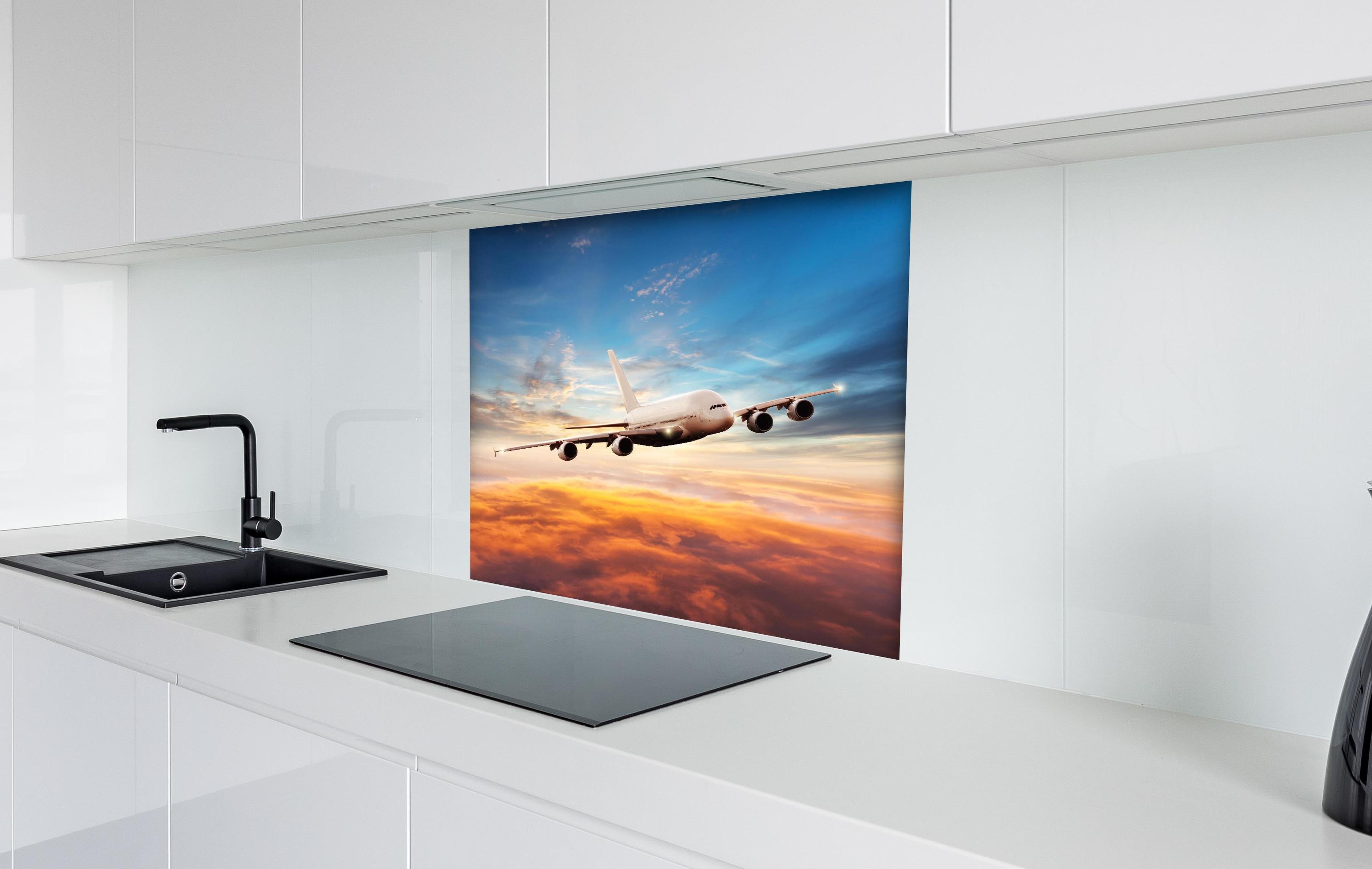 Spritzschutz - Jet im Sonnenuntergang über Wolken hinter einem Cerankochfeld zwischen Holz-Kochutensilien