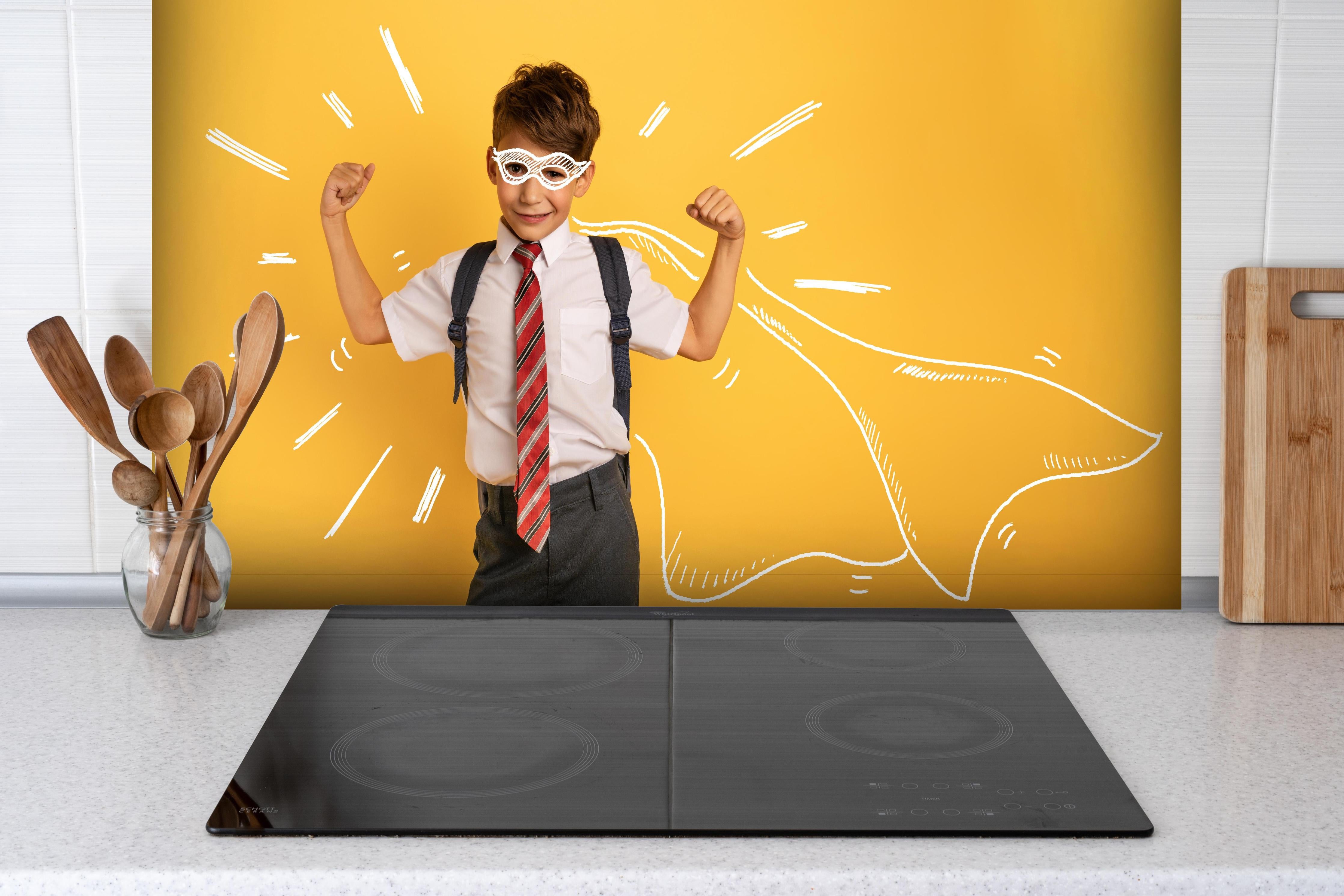 Spritzschutz - Junger Schüler hinter einem Cerankochfeld zwischen Holz-Kochutensilien