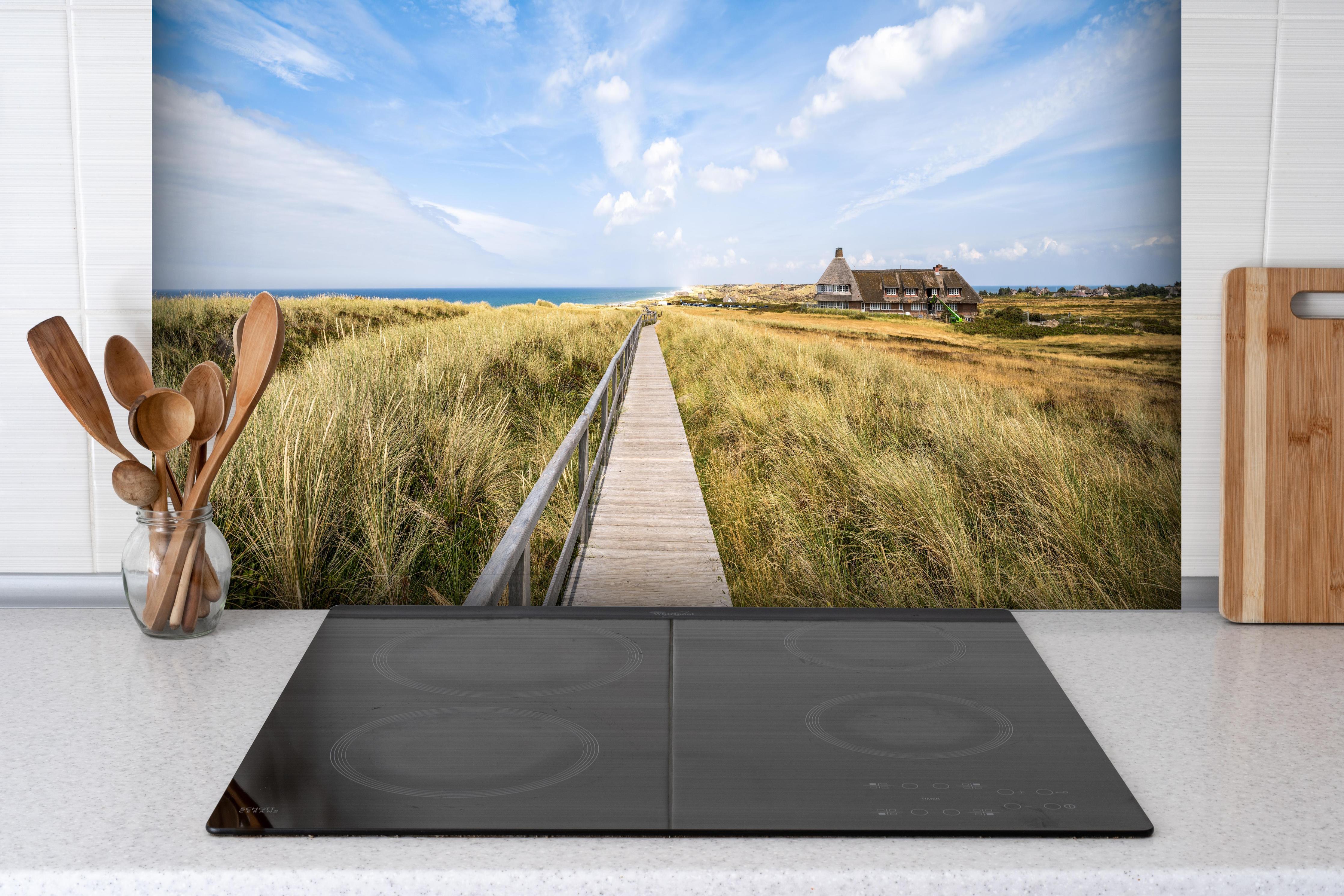 Spritzschutz - Kampen Landschaft hinter einem Cerankochfeld zwischen Holz-Kochutensilien