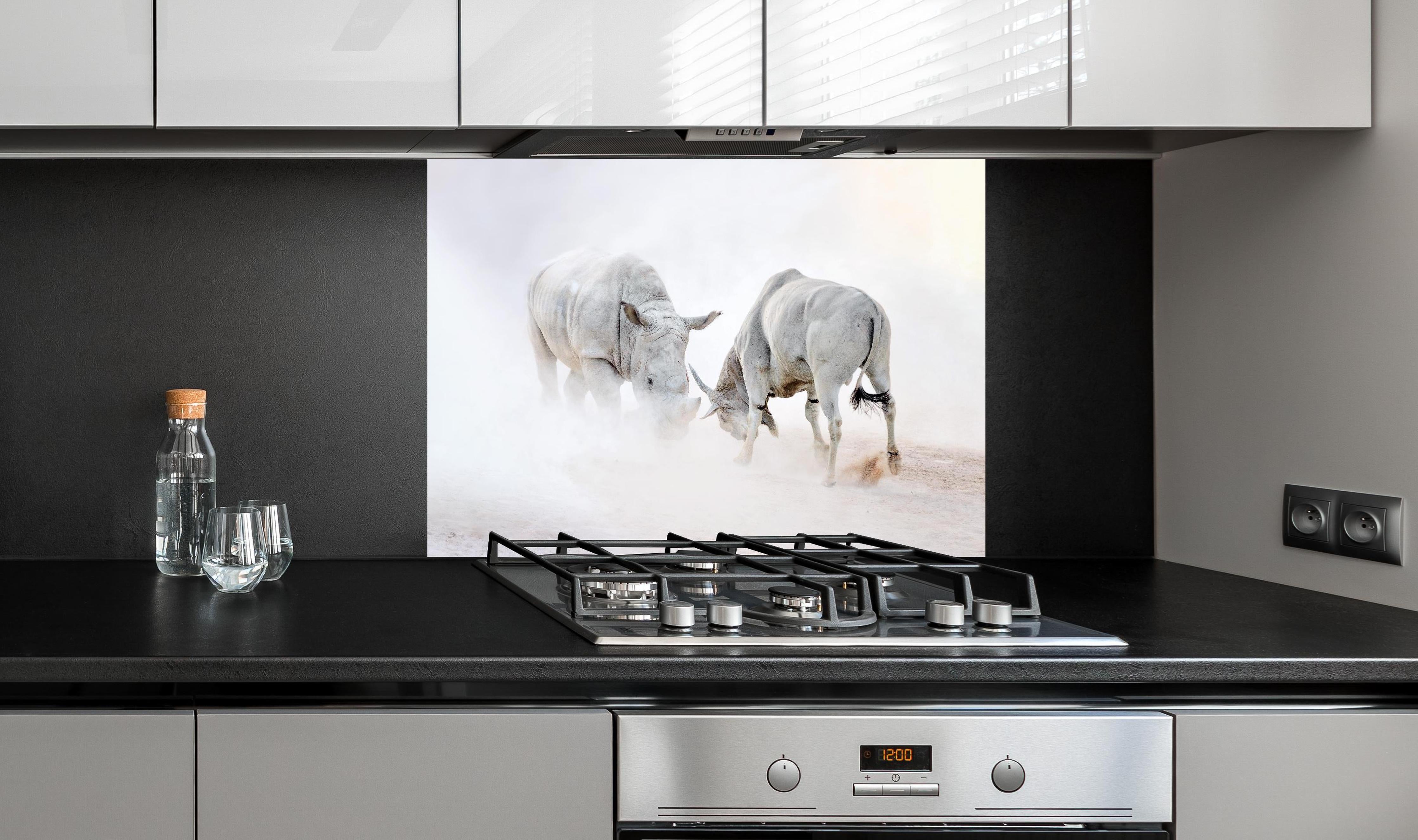 Spritzschutz - Kampf zwischen Nashorn und Oryx hinter einem Cerankochfeld zwischen Holz-Kochutensilien