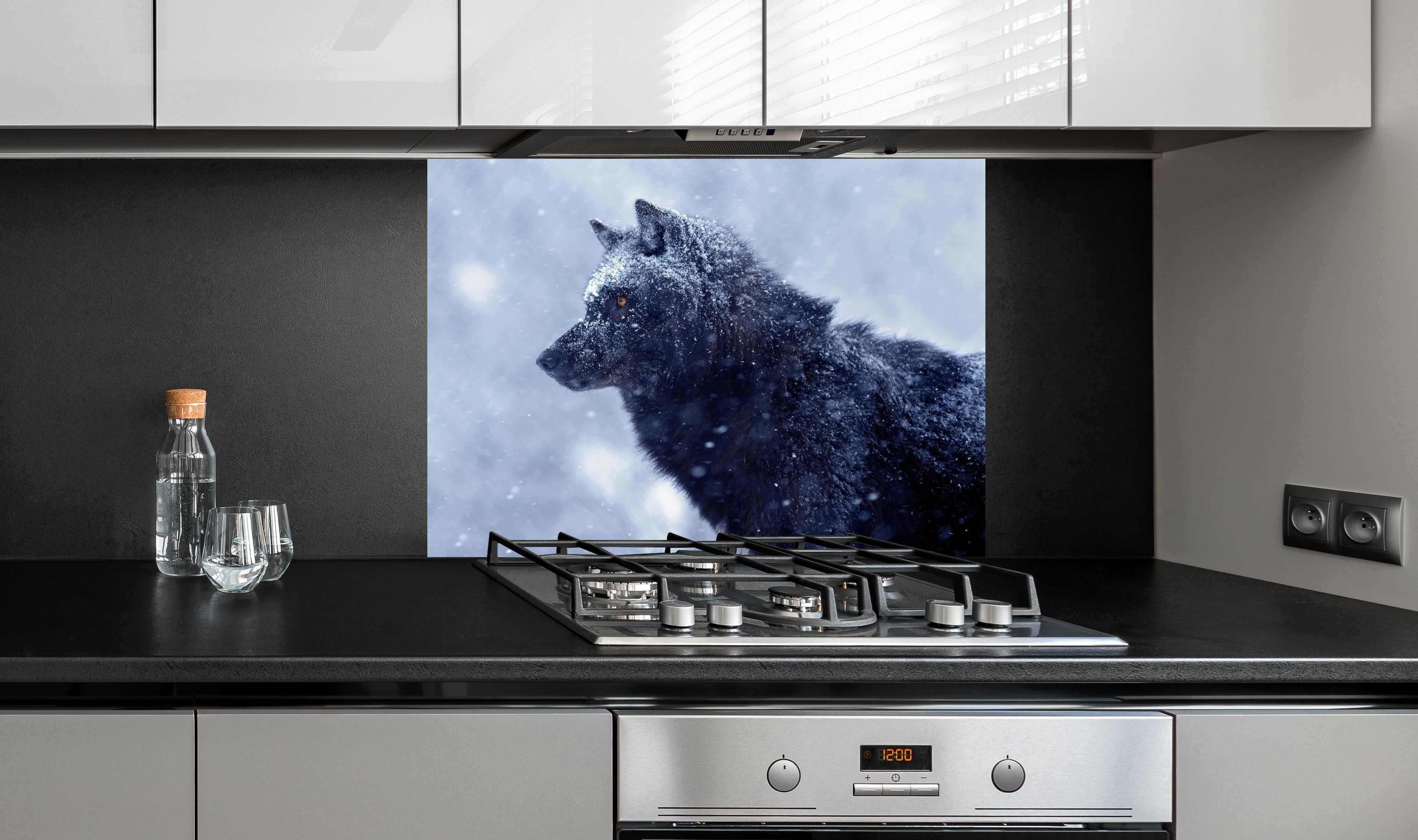 Spritzschutz - Kanadischer Wolf im Schneefall hinter einem Cerankochfeld zwischen Holz-Kochutensilien