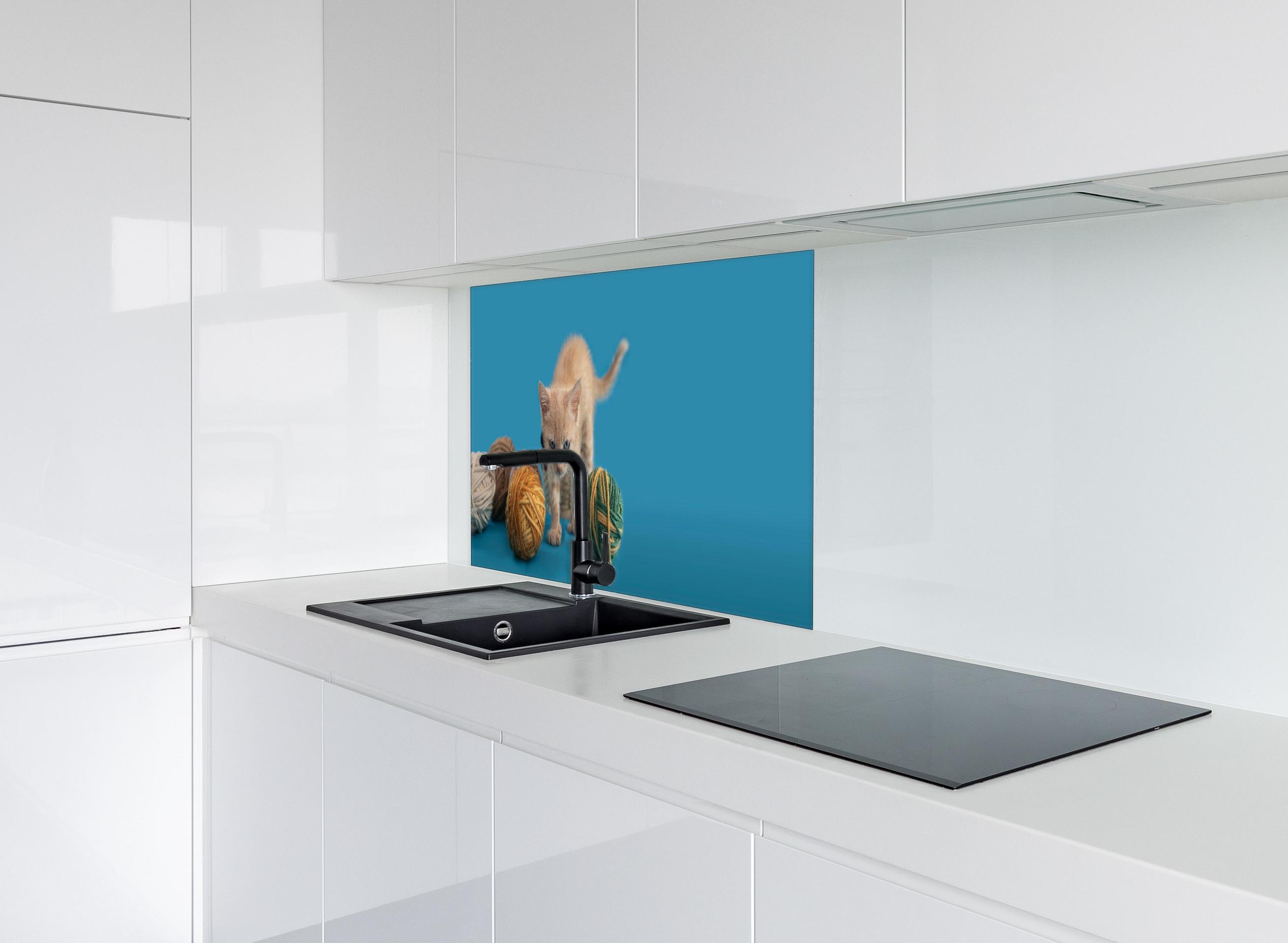 Spritzschutz - Katzenbaby spielt mit Wollknollen hinter einem Cerankochfeld zwischen Holz-Kochutensilien