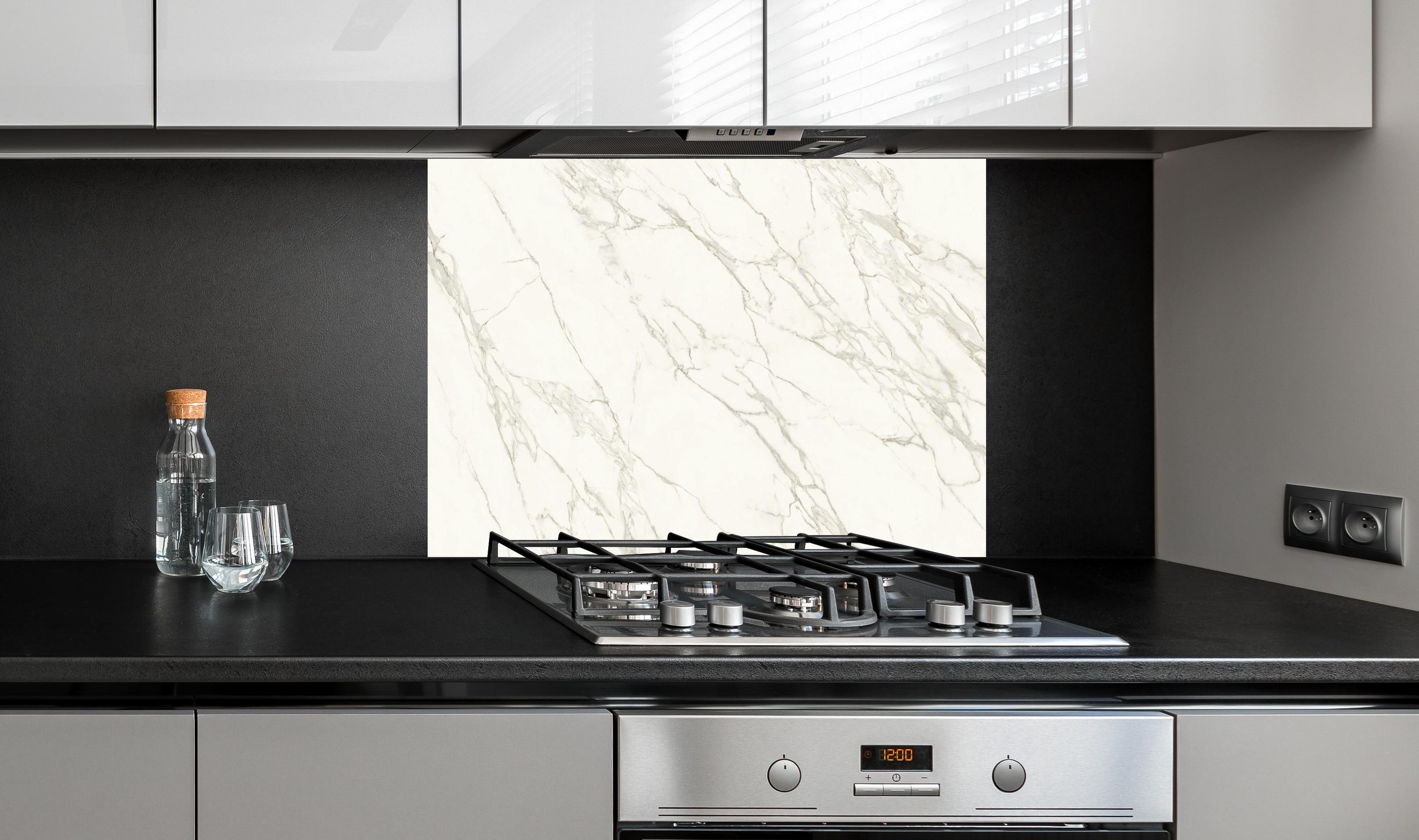 Spritzschutz - Keramik Calacatta Vein hinter einem Cerankochfeld zwischen Holz-Kochutensilien