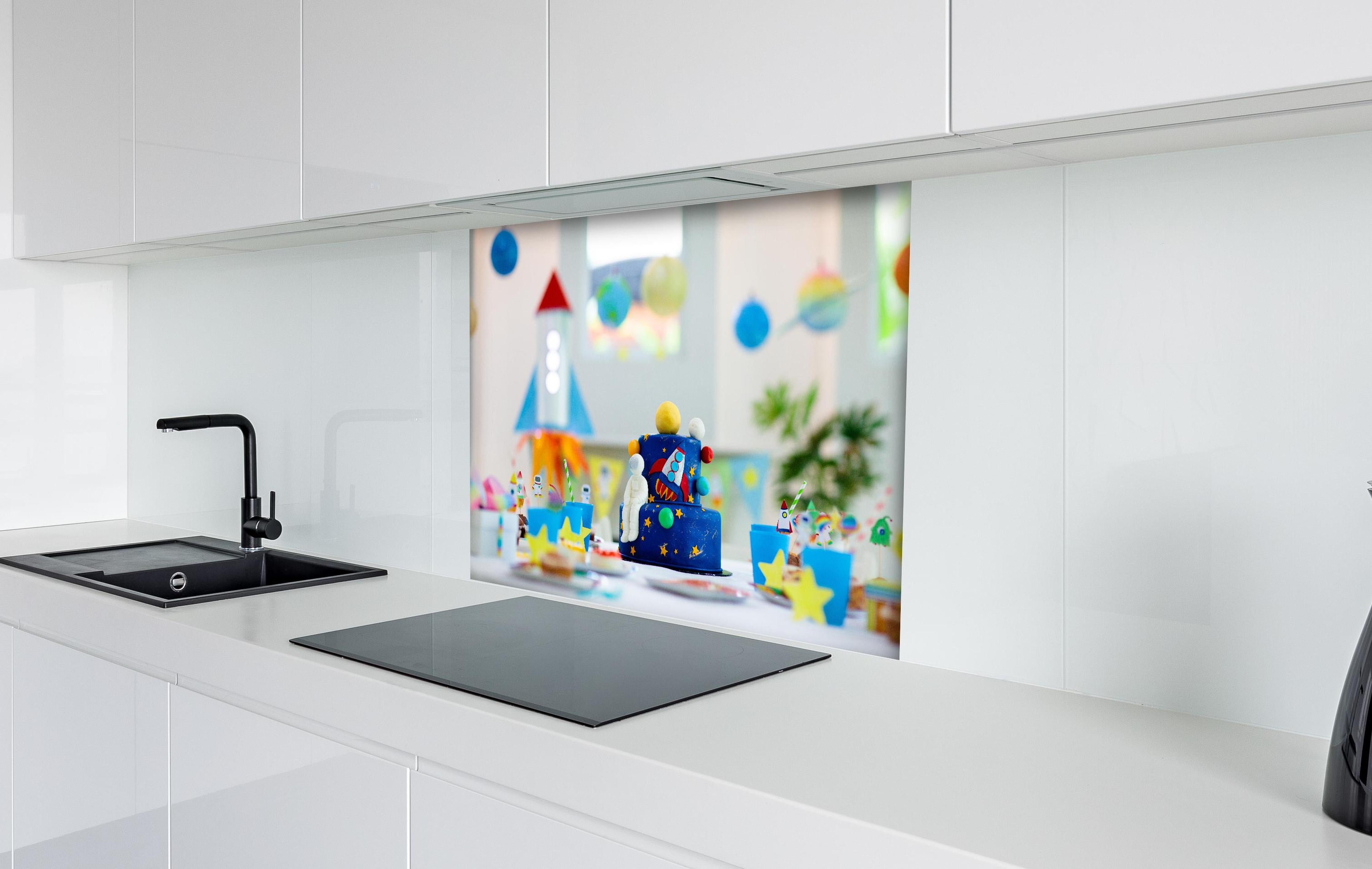 Spritzschutz - Kindergeburtstagsfeier zum Thema Weltraum mit Kuchen. hinter einem Cerankochfeld zwischen Holz-Kochutensilien