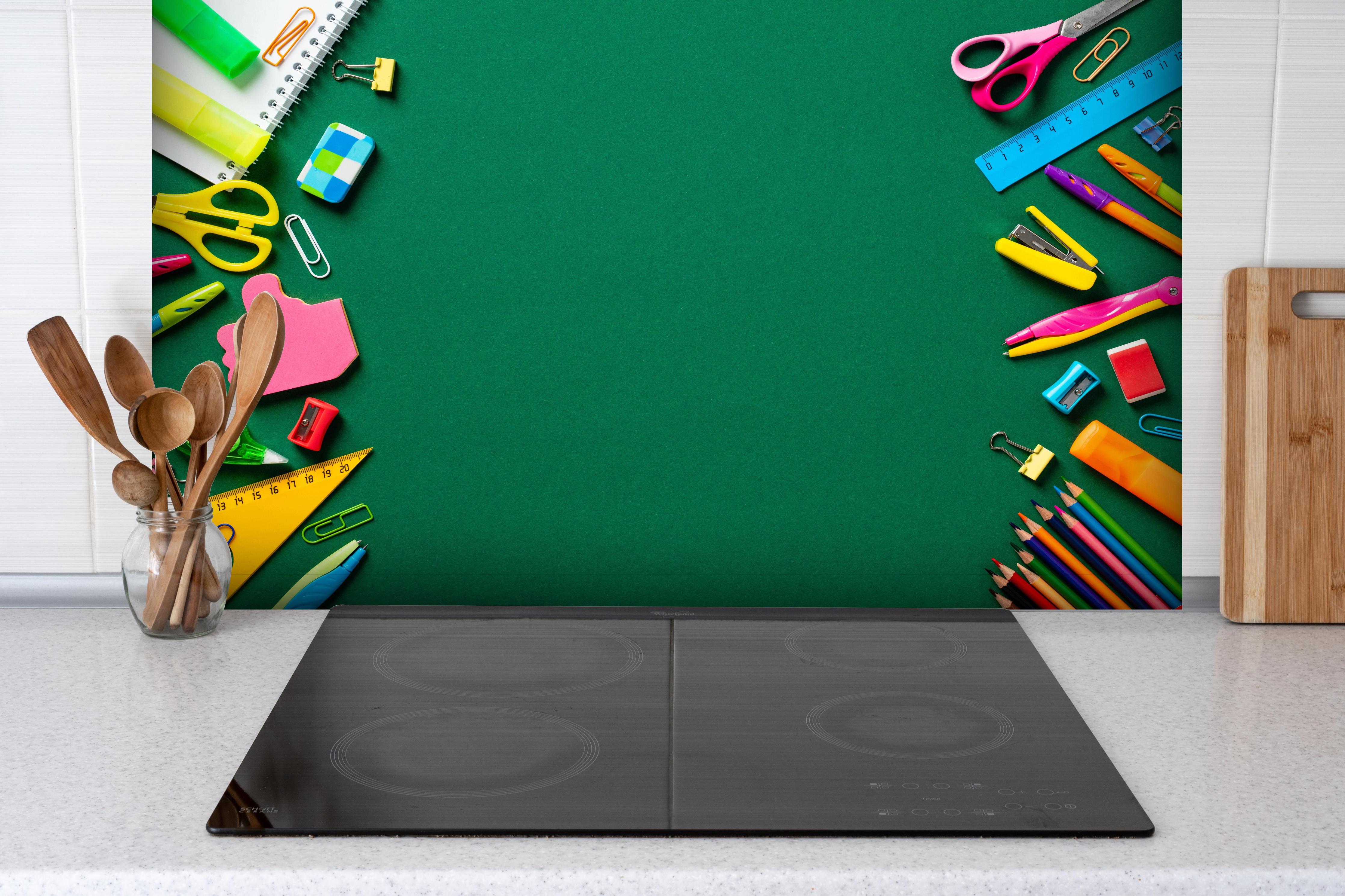 Spritzschutz - Kindermotiv - Schulsachen hinter einem Cerankochfeld zwischen Holz-Kochutensilien