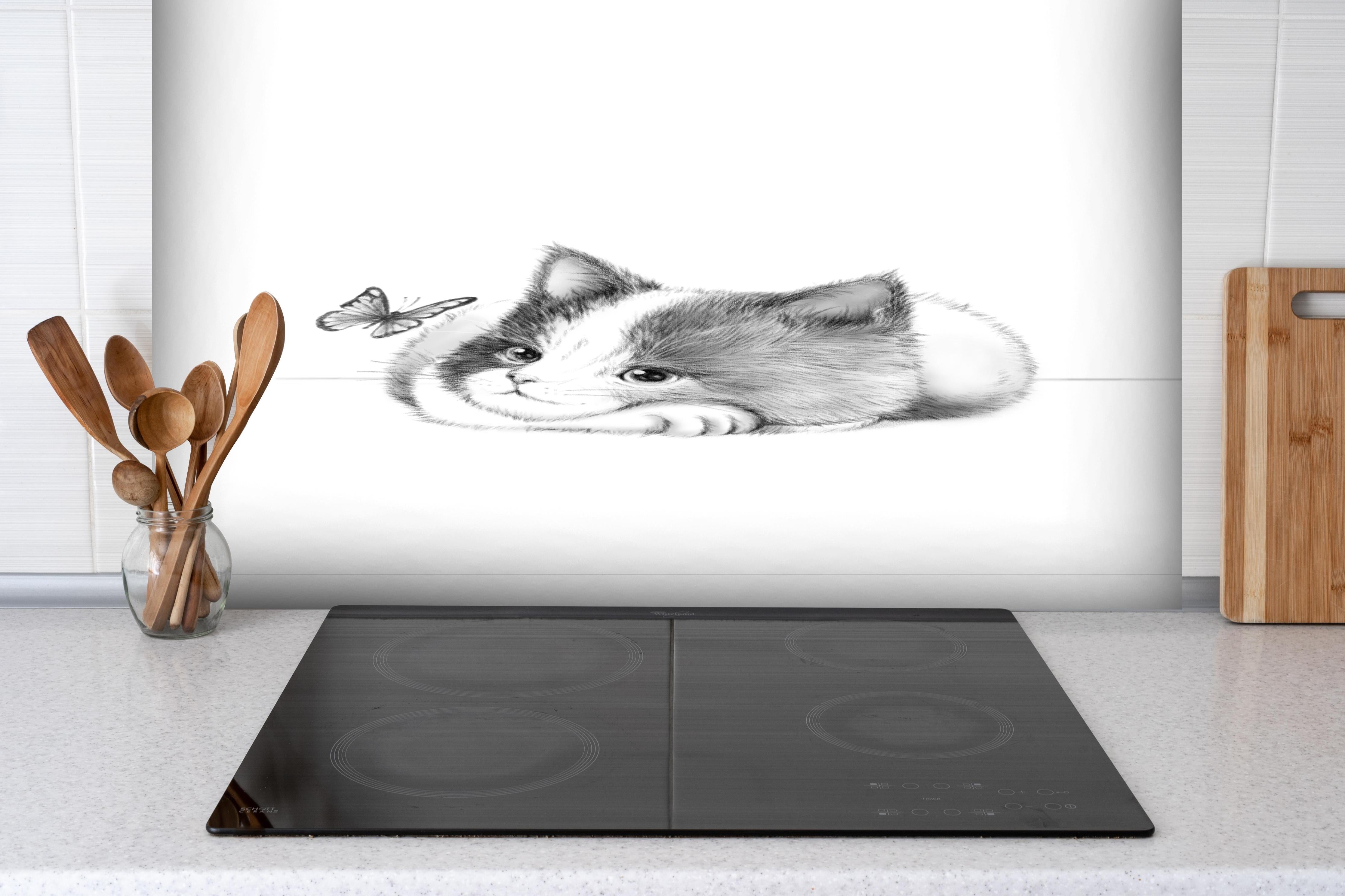 Spritzschutz - Kindermotiv einer Katze - Schwarz-weiß hinter einem Cerankochfeld zwischen Holz-Kochutensilien