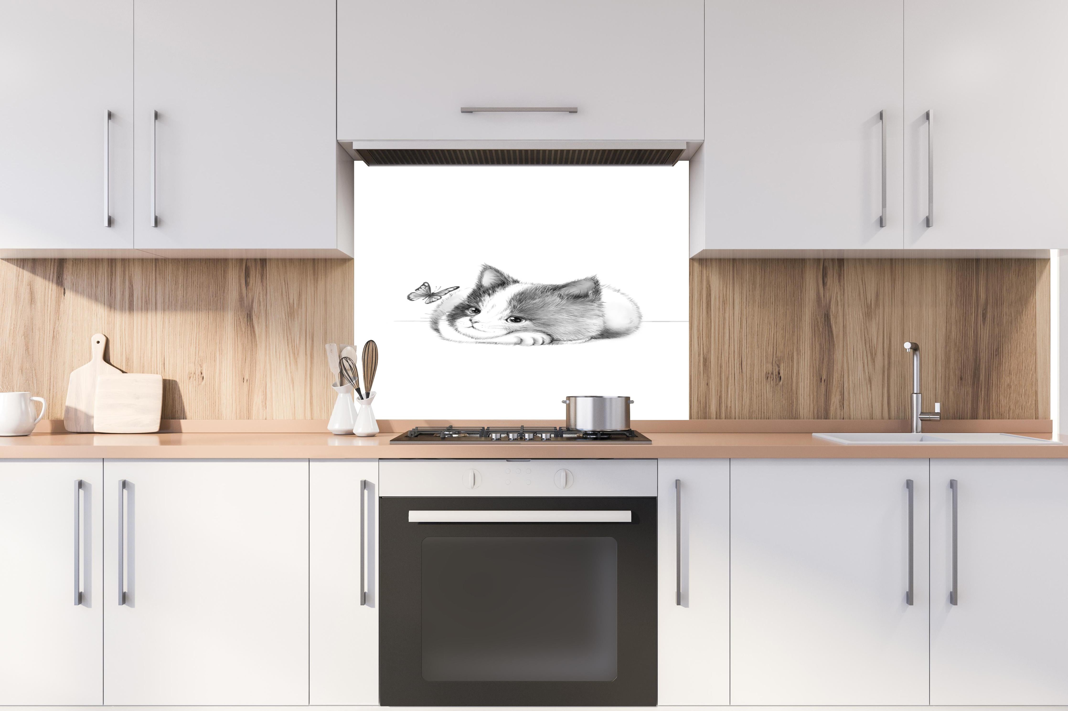 Spritzschutz - Kindermotiv einer Katze - Schwarz-weiß hinter einem Cerankochfeld zwischen Holz-Kochutensilien