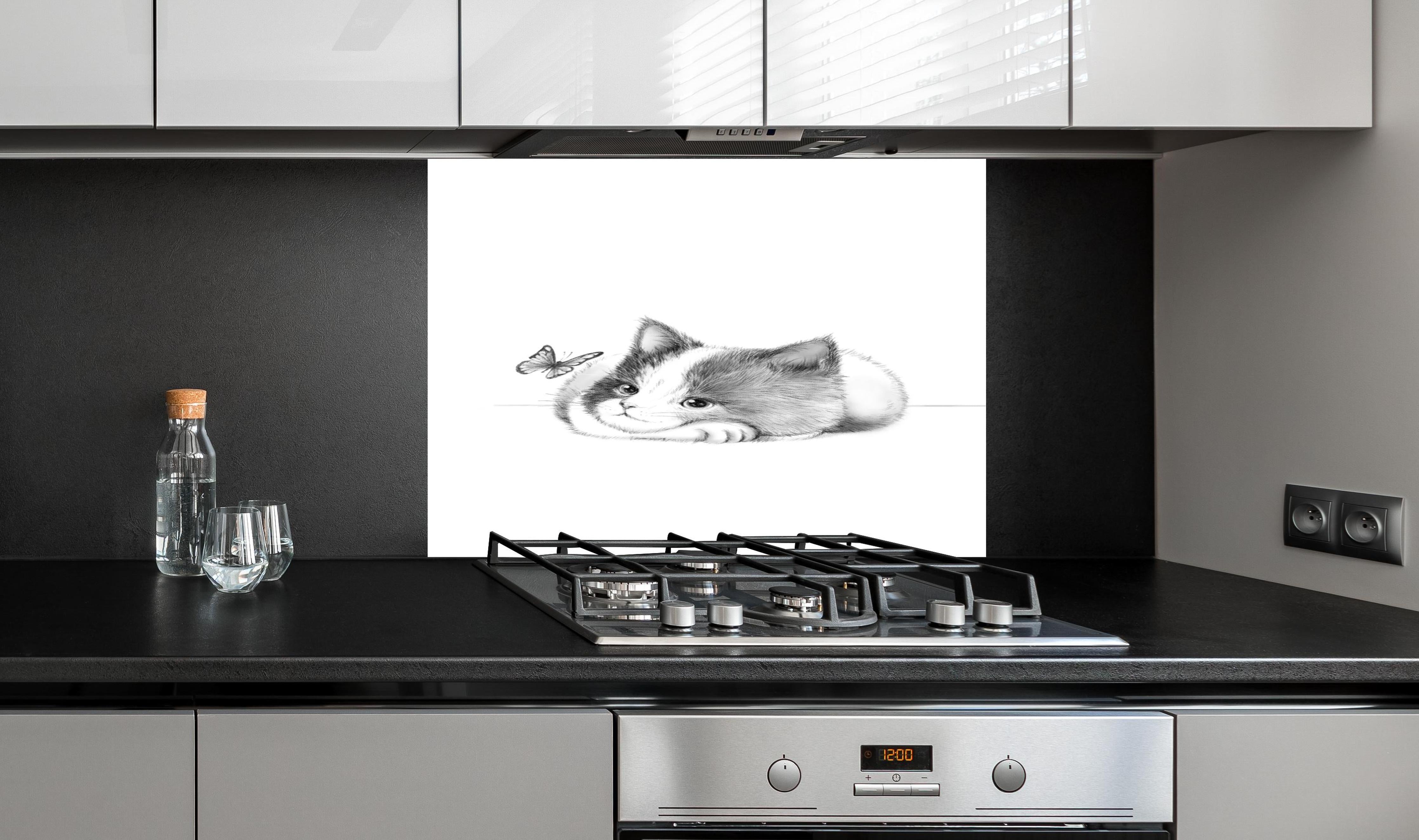 Spritzschutz - Kindermotiv einer Katze - Schwarz-weiß hinter einem Cerankochfeld zwischen Holz-Kochutensilien