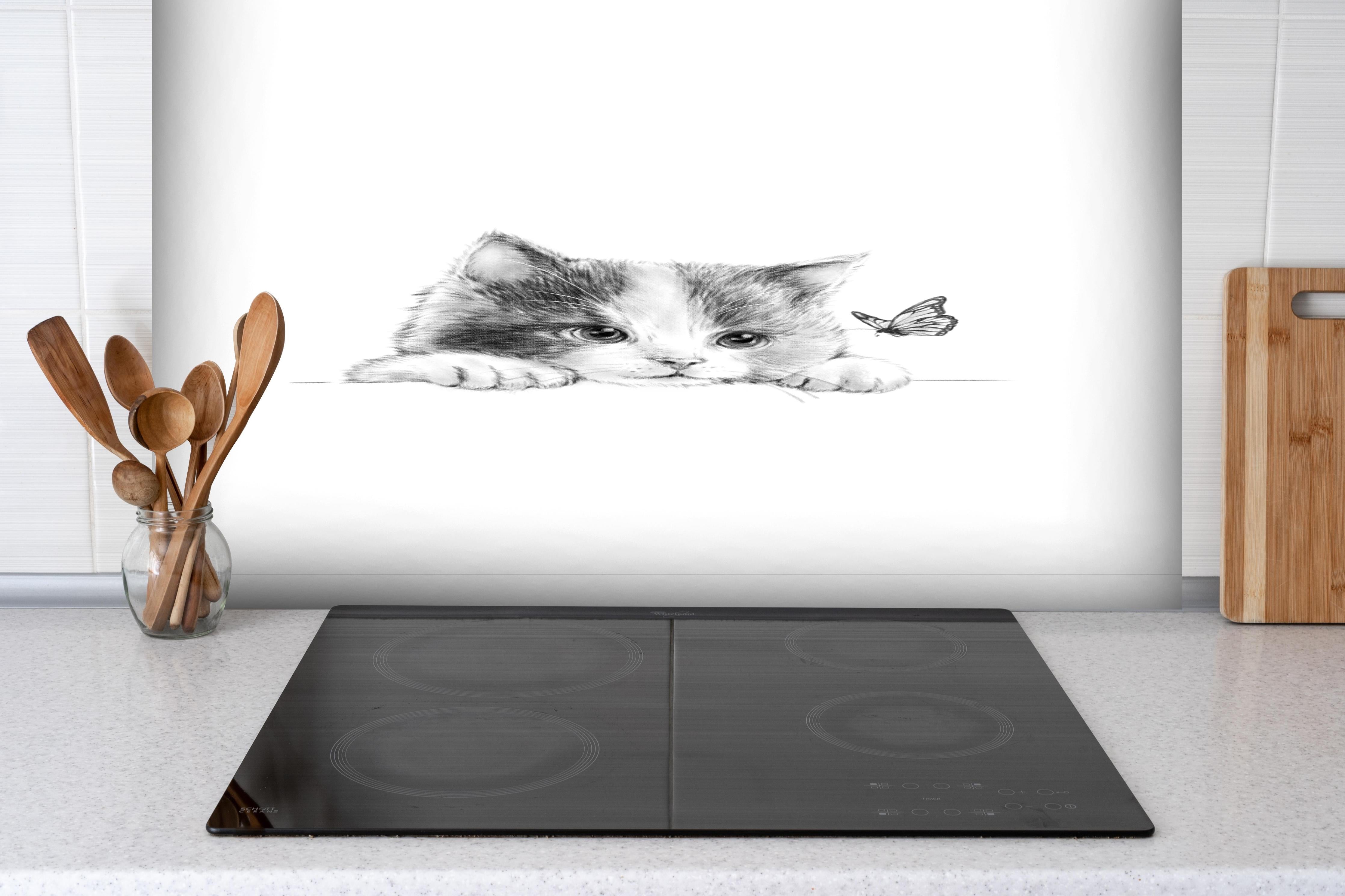Spritzschutz - Kindermotiv einer Katze - schwarz-weiß hinter einem Cerankochfeld zwischen Holz-Kochutensilien