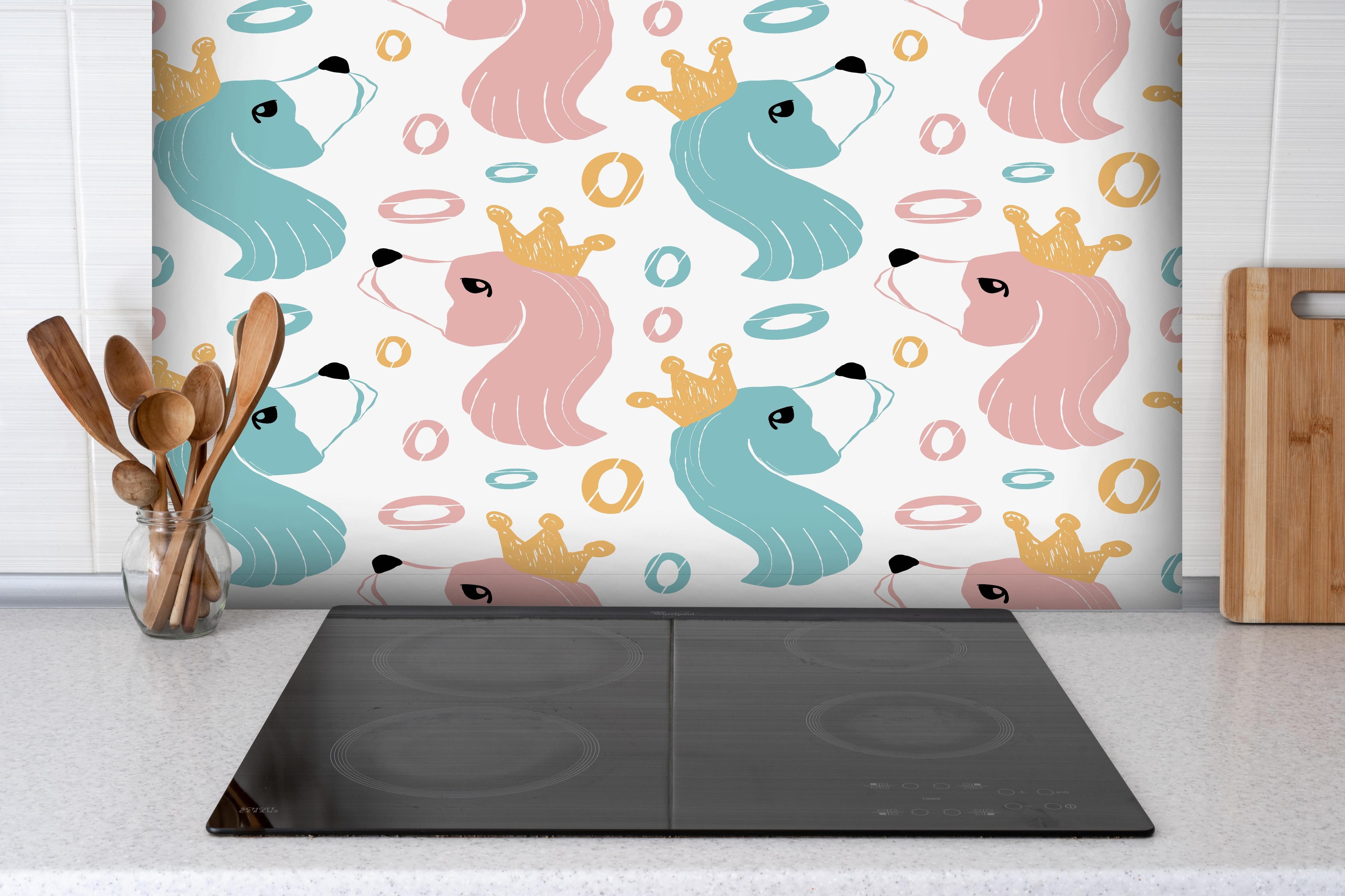 Spritzschutz - Kindliches Einhorn-Motiv mit Kronen hinter einem Cerankochfeld zwischen Holz-Kochutensilien