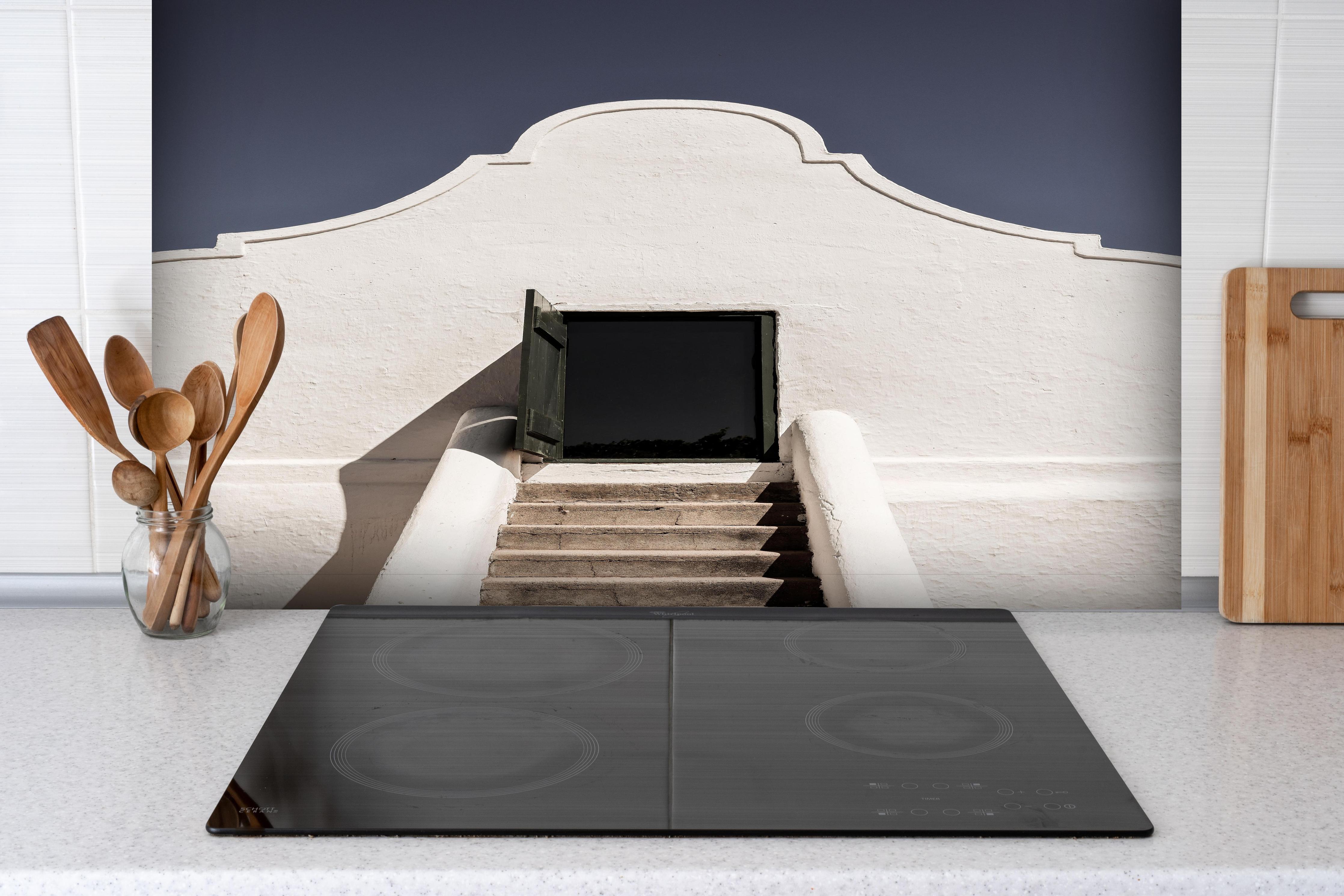 Spritzschutz - Klassische Kap-Holländische Gebäudetür hinter einem Cerankochfeld zwischen Holz-Kochutensilien