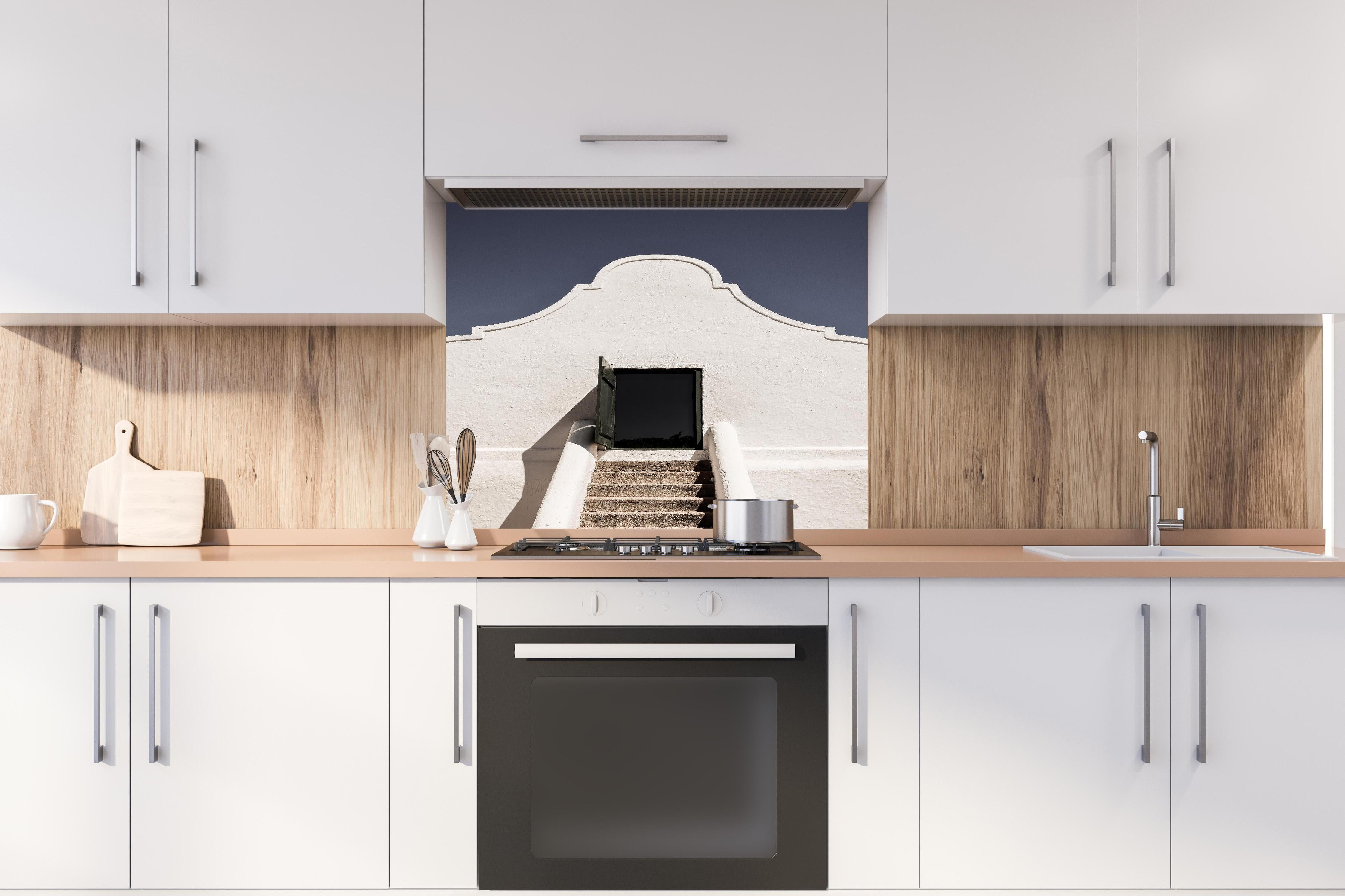 Spritzschutz - Klassische Kap-Holländische Gebäudetür hinter einem Cerankochfeld zwischen Holz-Kochutensilien