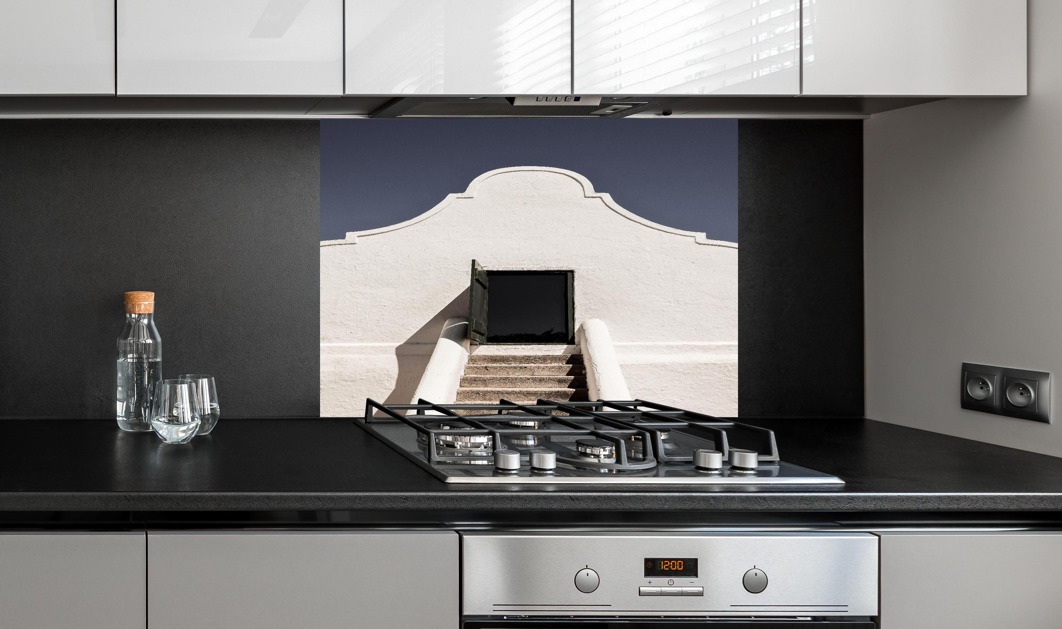 Spritzschutz - Klassische Kap-Holländische Gebäudetür hinter einem Cerankochfeld zwischen Holz-Kochutensilien