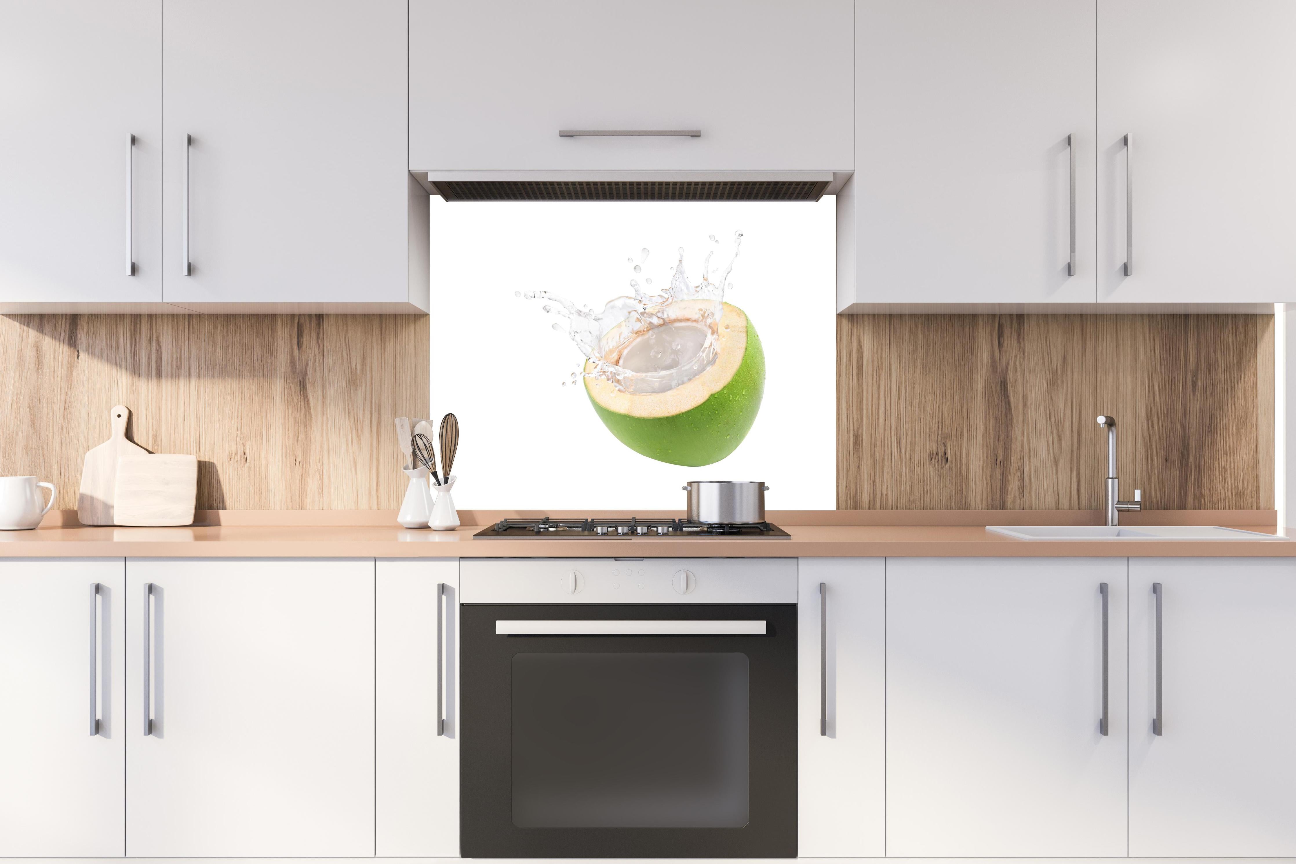 Spritzschutz - Kokosnuss mit Kokosmilch hinter einem Cerankochfeld zwischen Holz-Kochutensilien