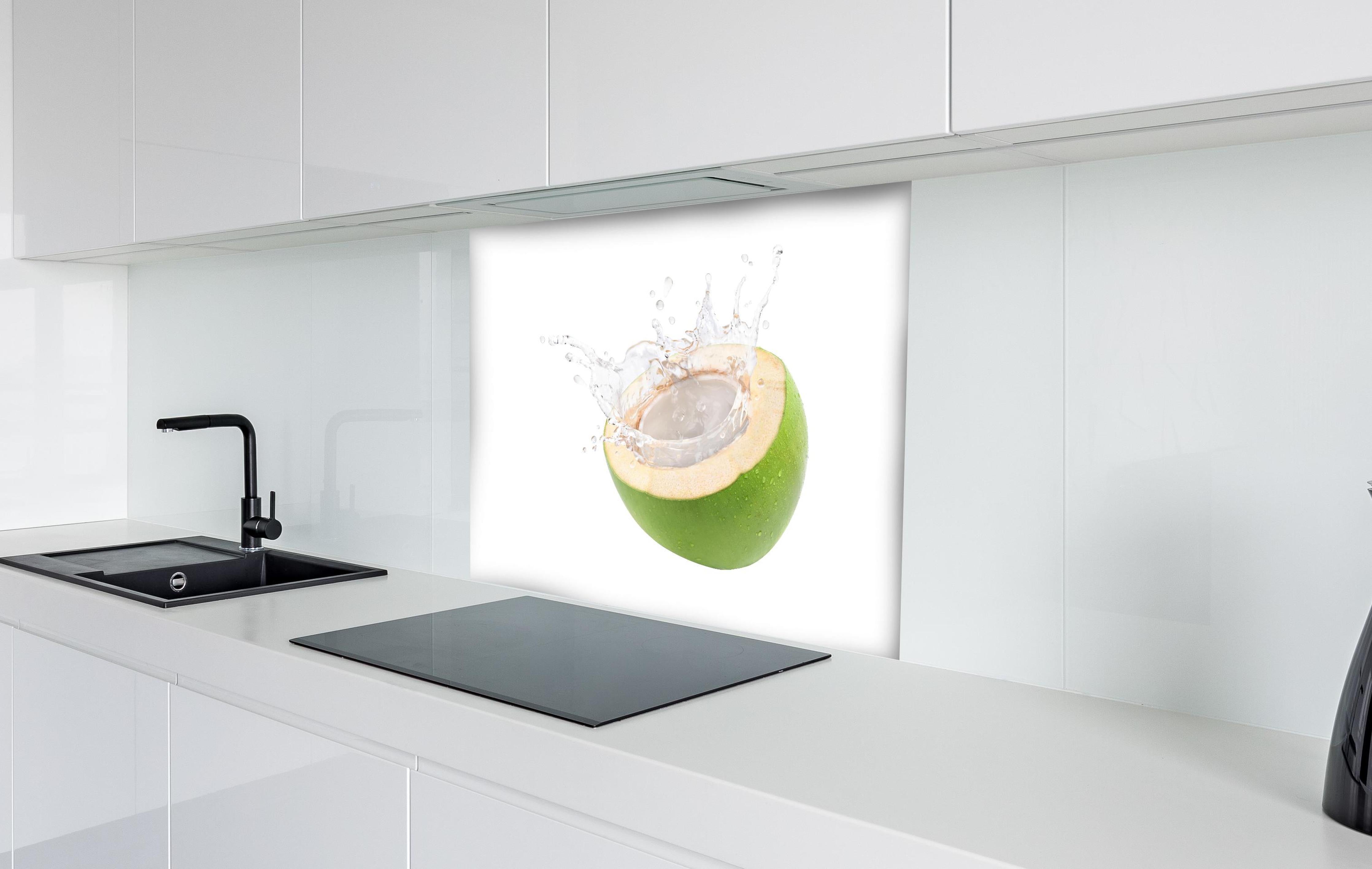 Spritzschutz - Kokosnuss mit Kokosmilch hinter einem Cerankochfeld zwischen Holz-Kochutensilien
