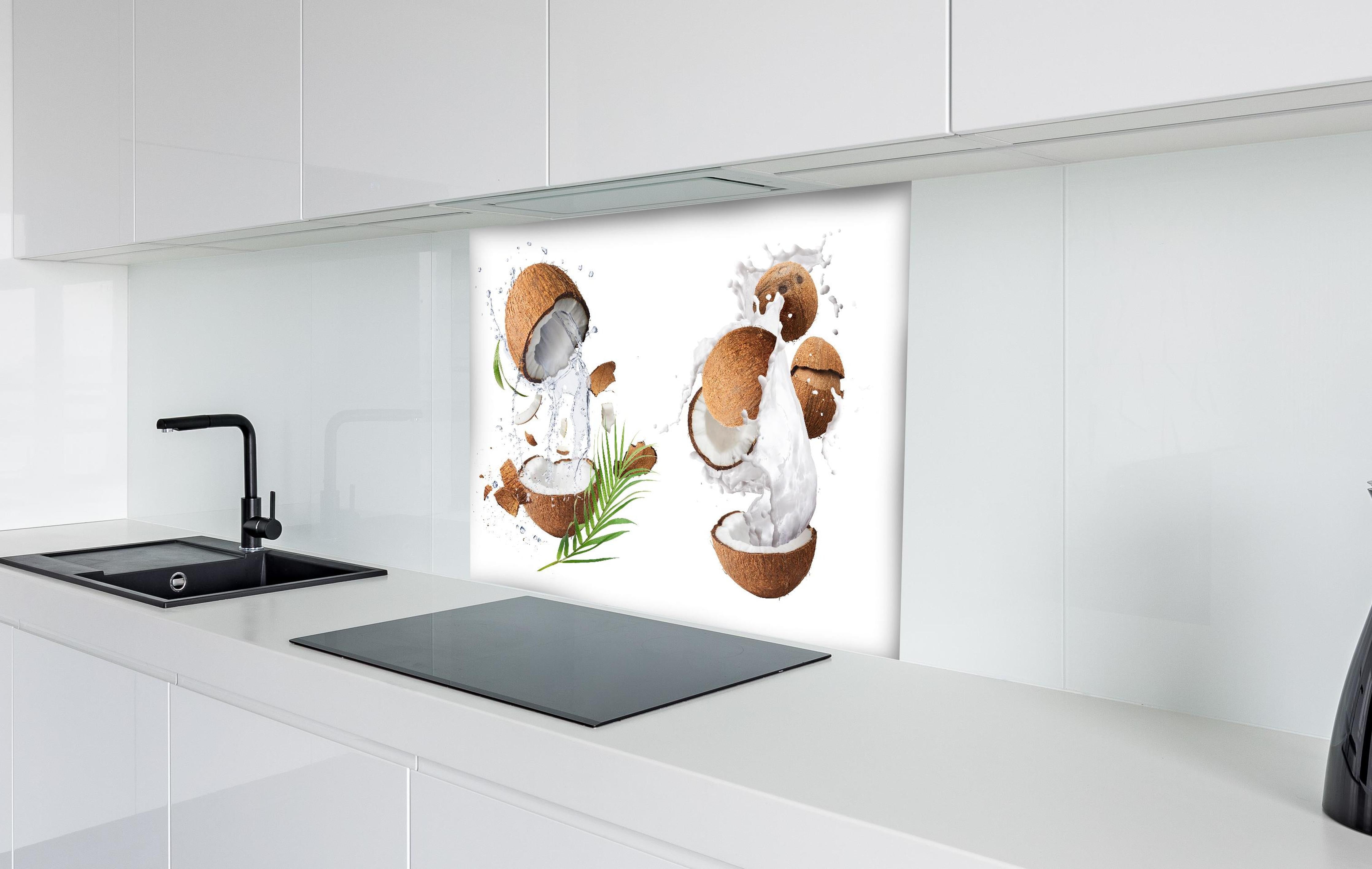 Spritzschutz - Kokosnuss mit frischem Milchspritzer hinter einem Cerankochfeld zwischen Holz-Kochutensilien