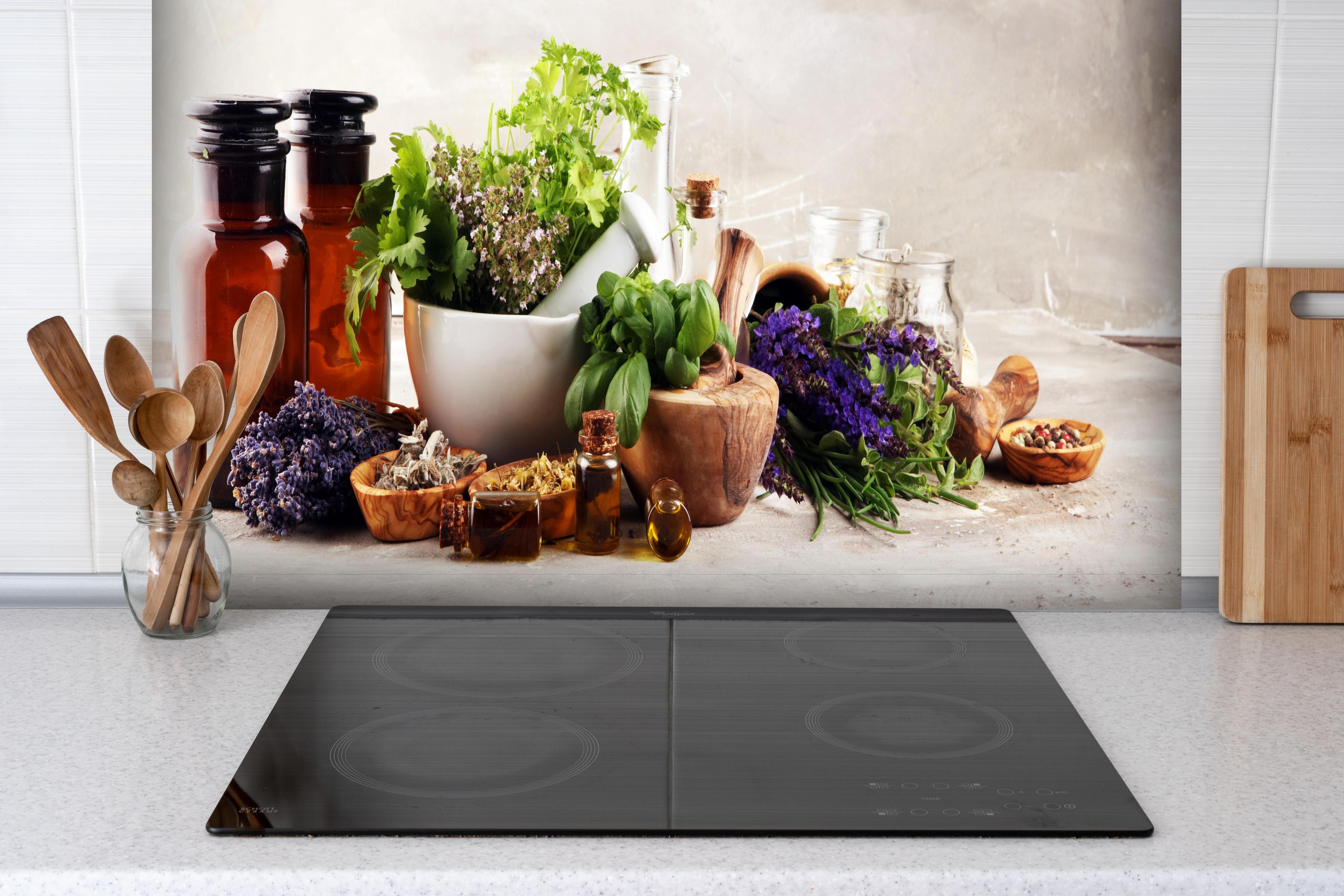 Spritzschutz - Kräuter- & Aromatherapie hinter einem Cerankochfeld zwischen Holz-Kochutensilien